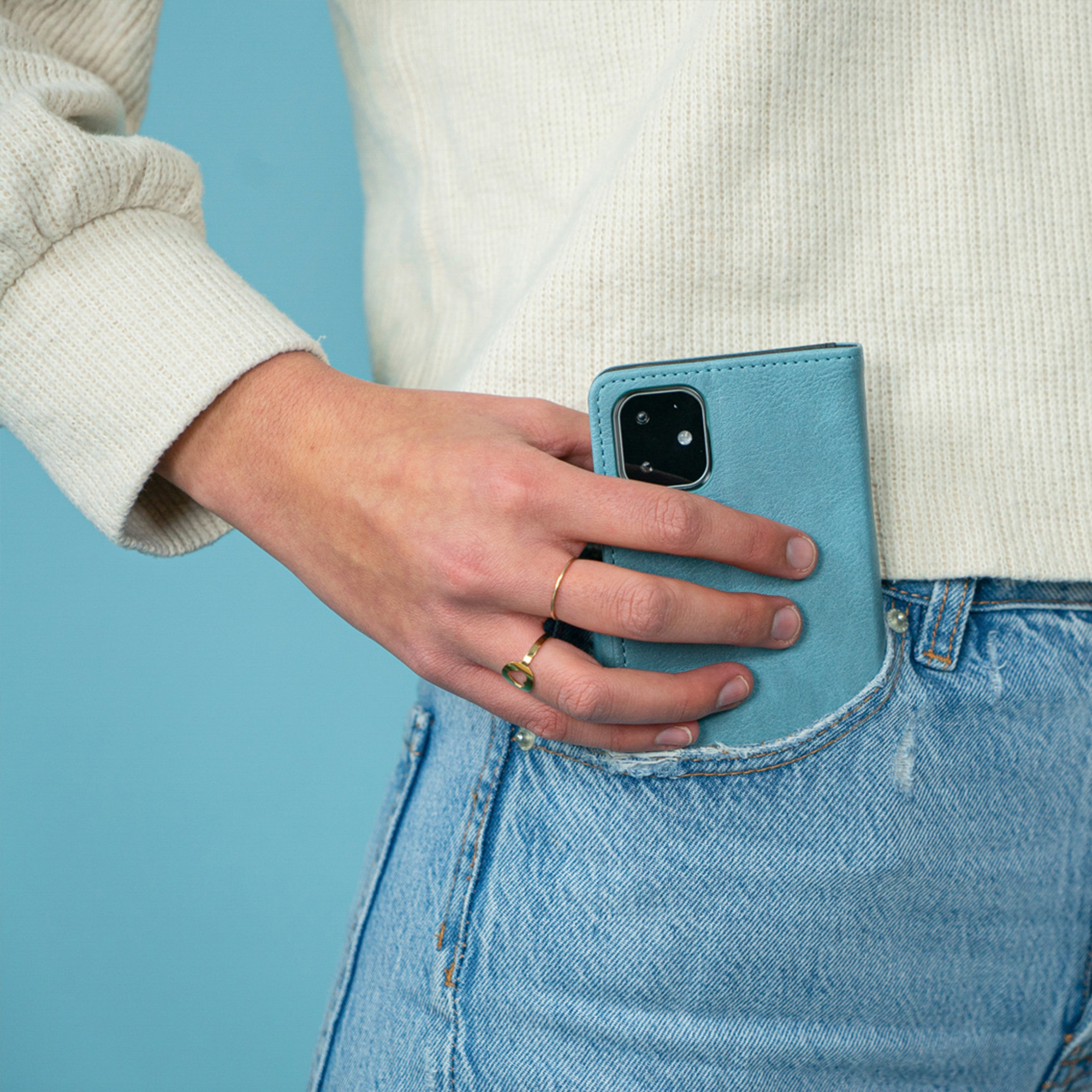 Una mano mette un telefono blu nella tasca dei jeans.