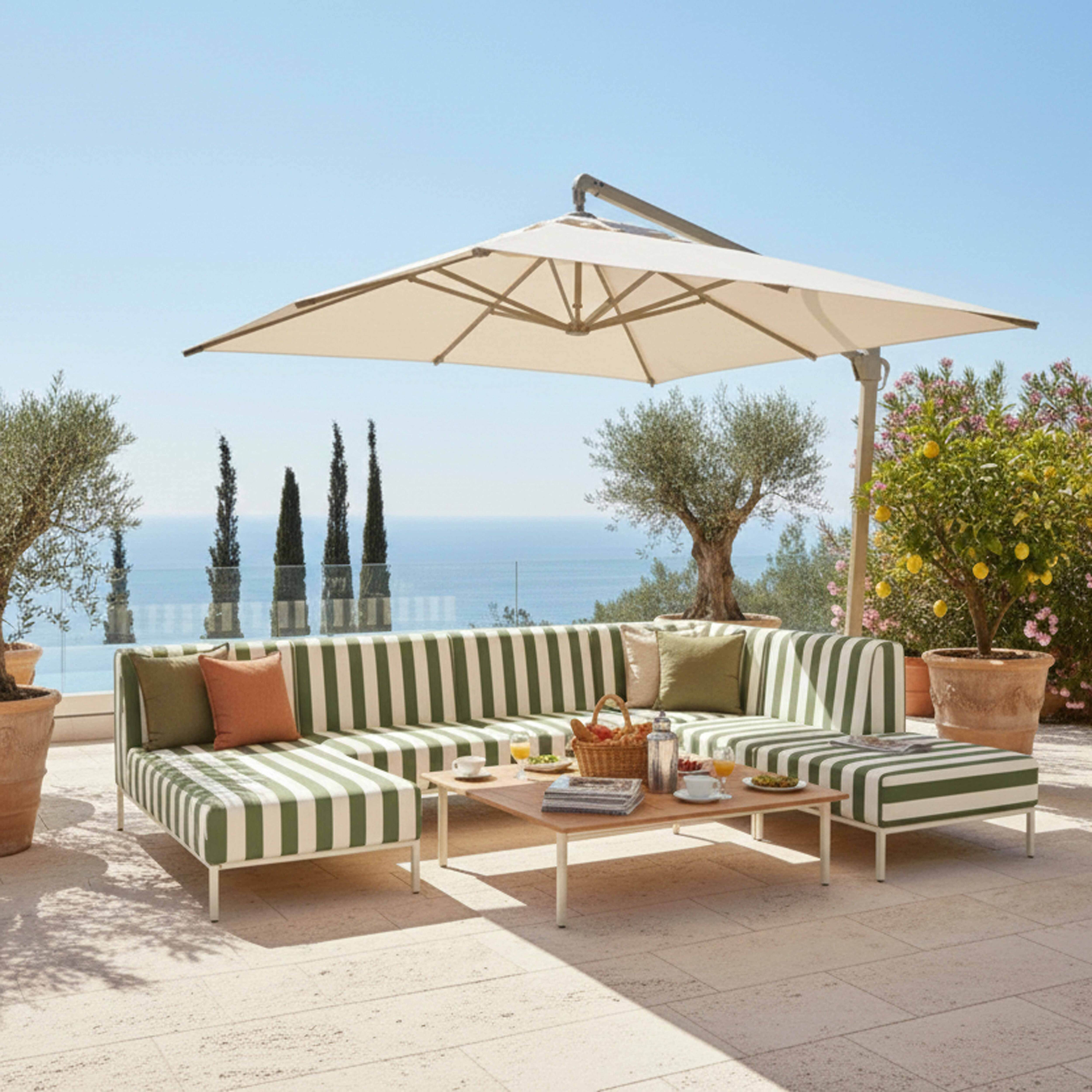 Ein gestreiftes Outdoor-Sofa mit Kissen, ein Tisch mit Snacks und Getränken, Sonnenschirm.