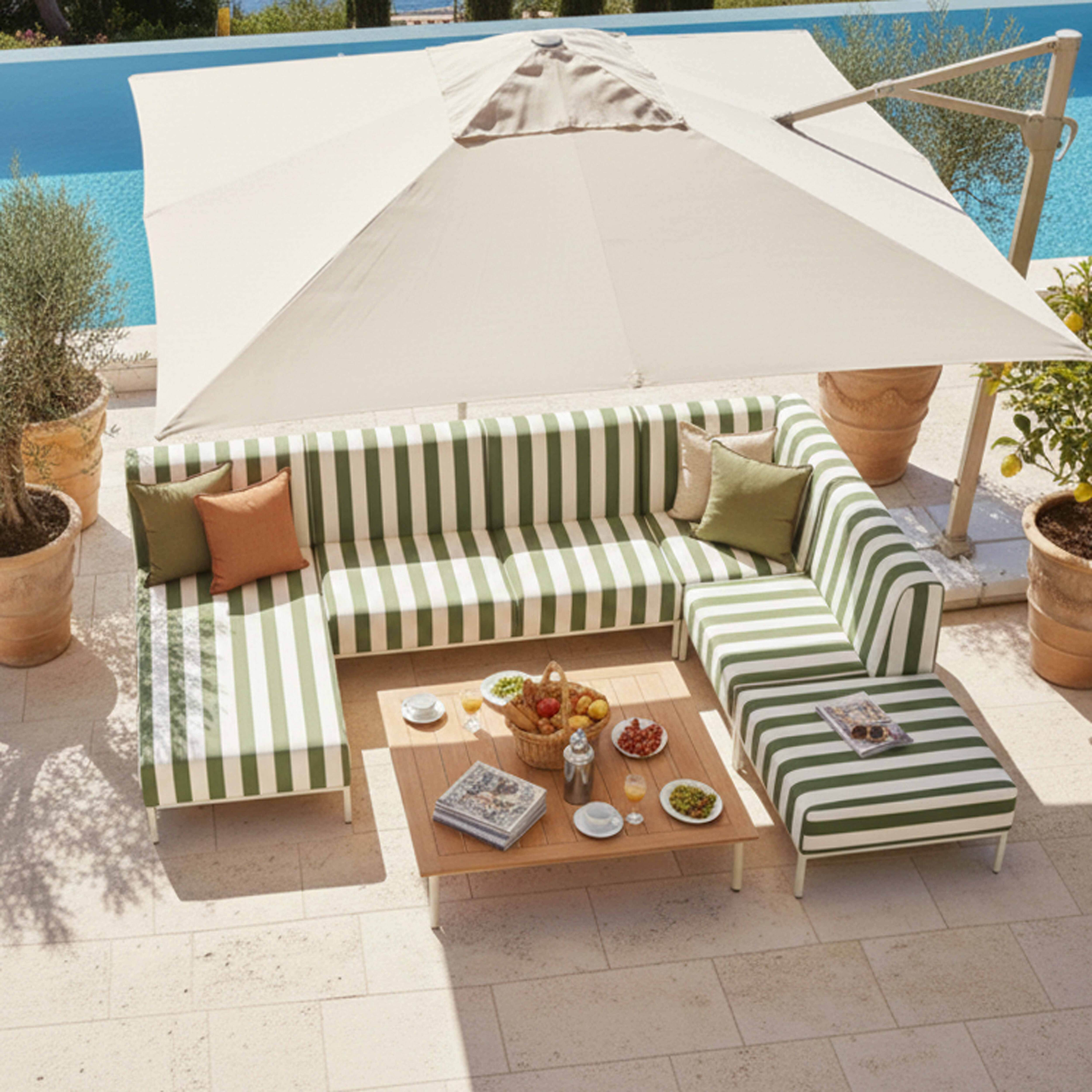 Ein gestreiftes Sofa mit Kissen und ein Tisch mit Snacks am Pool.