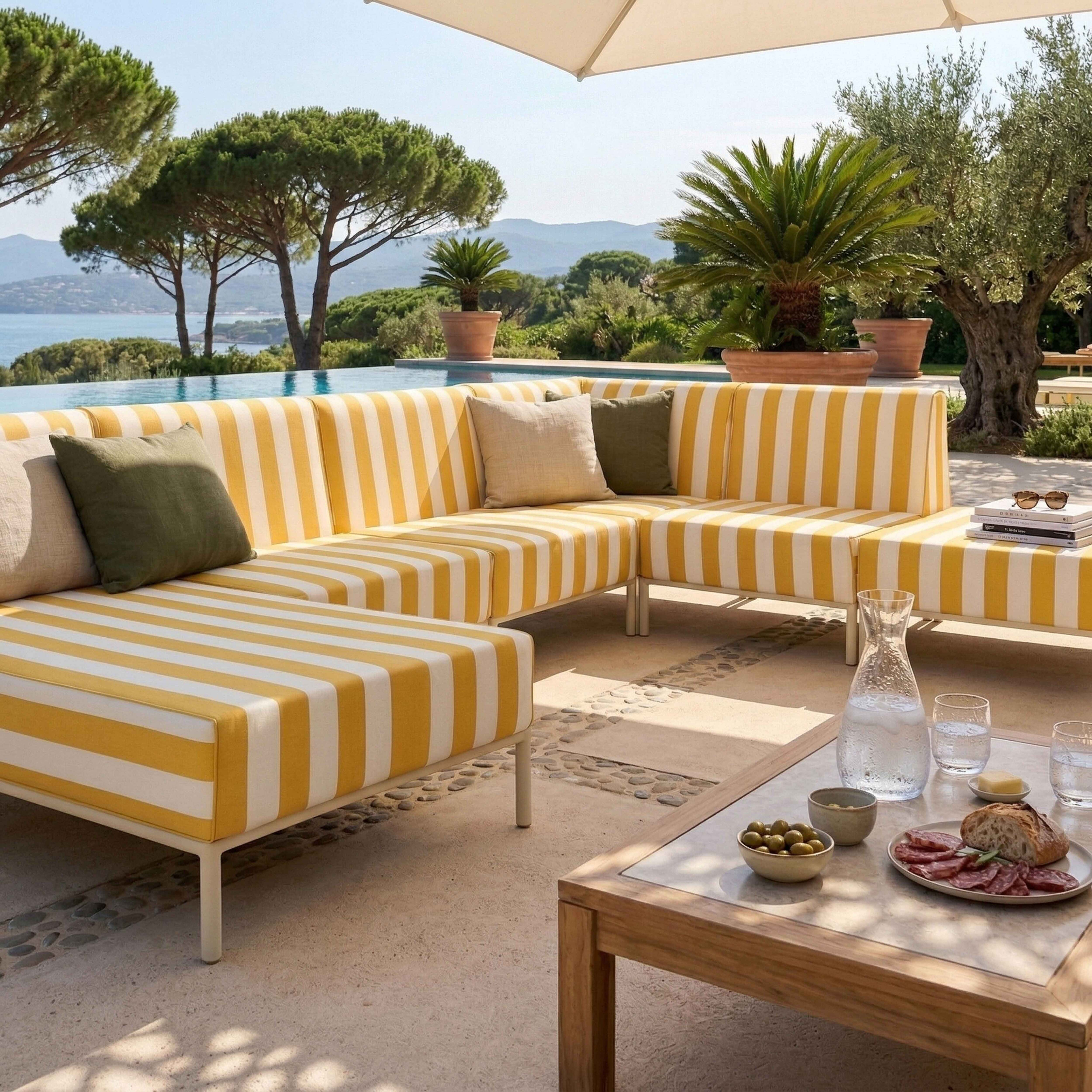 Ein gestreiftes Sofa im Freien mit einem Pool und Bergen im Hintergrund.