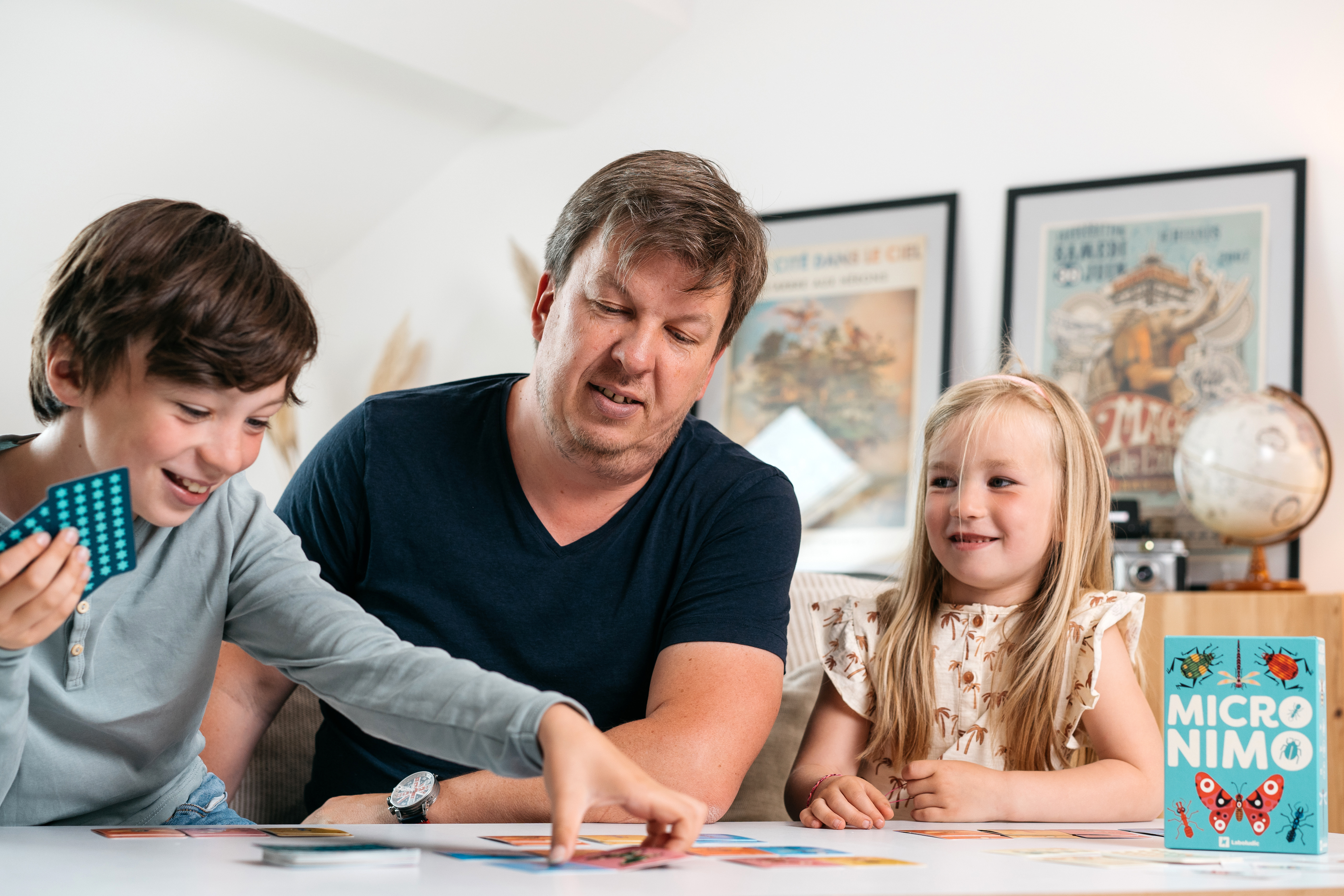 Familie spielt Brettspiel. Mann, Sohn und Tochter am Tisch.