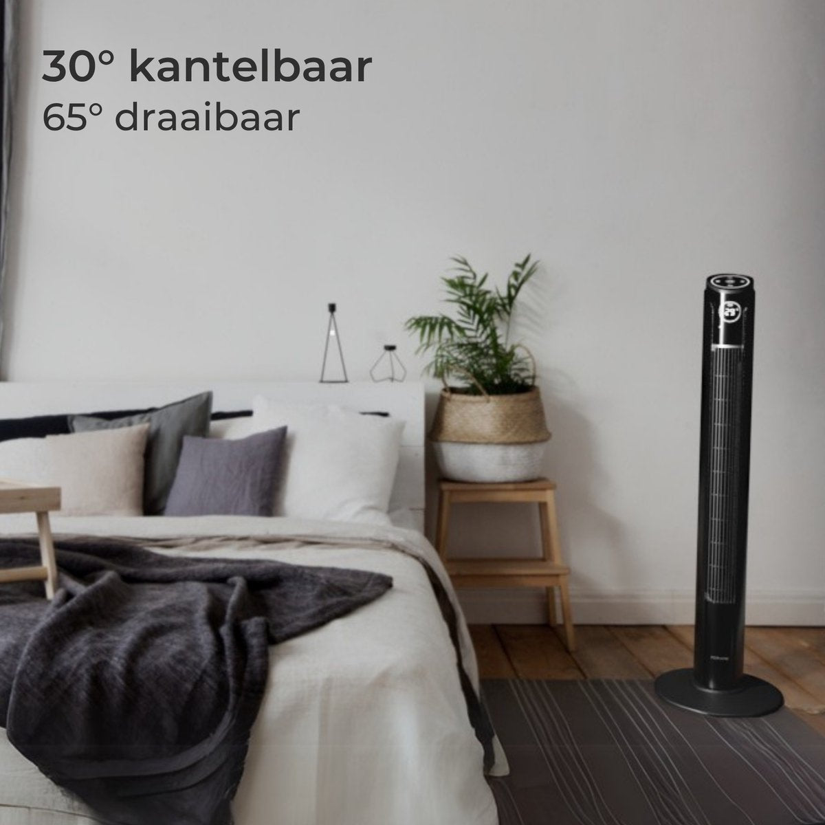 Ein schwarzer Turmventilator steht neben einem Bett mit weißen Laken und dunkler Decke.