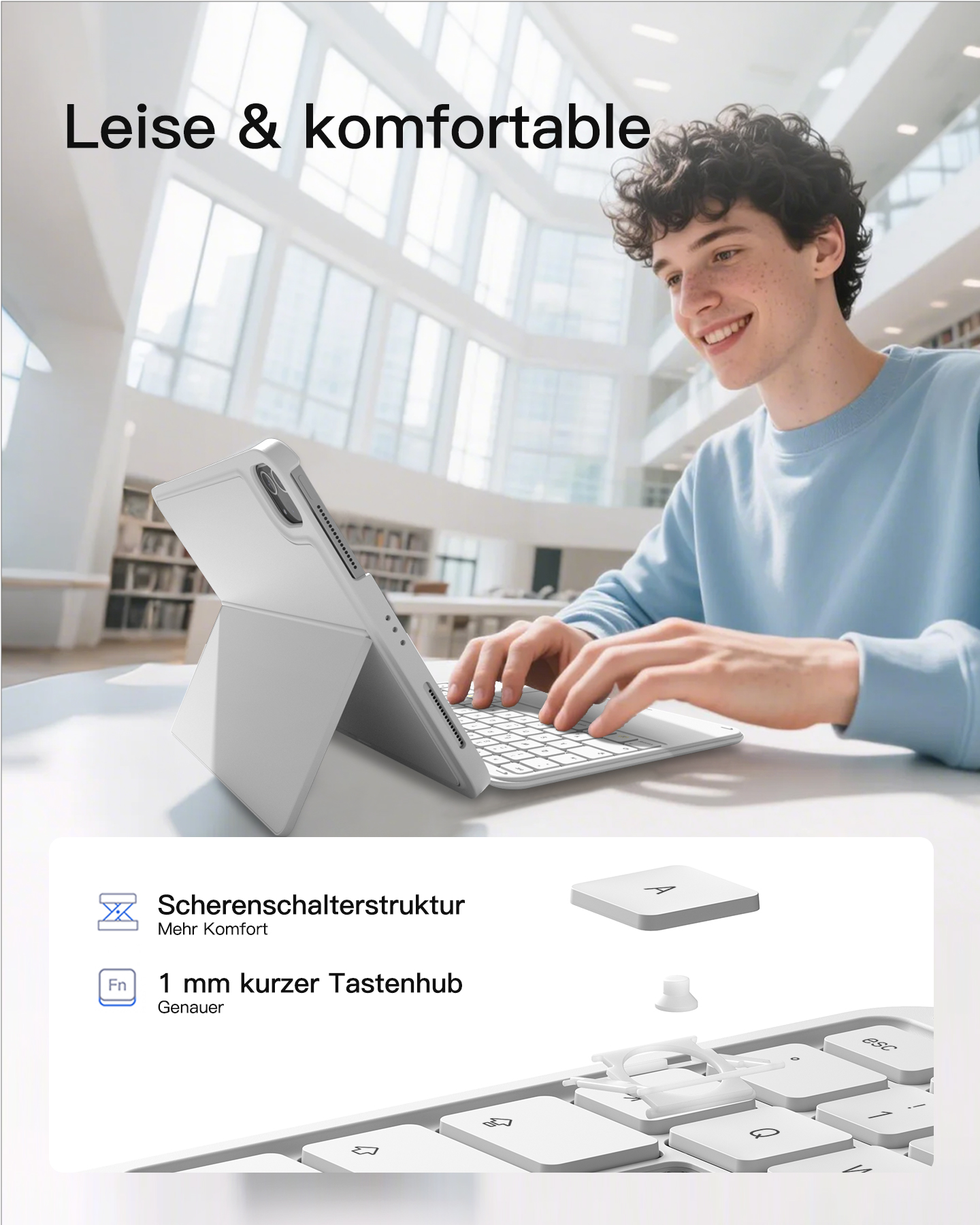 Ein junger Mann tippt auf einer Tastatur vor einem Tablet in einem modernen Gebäude.