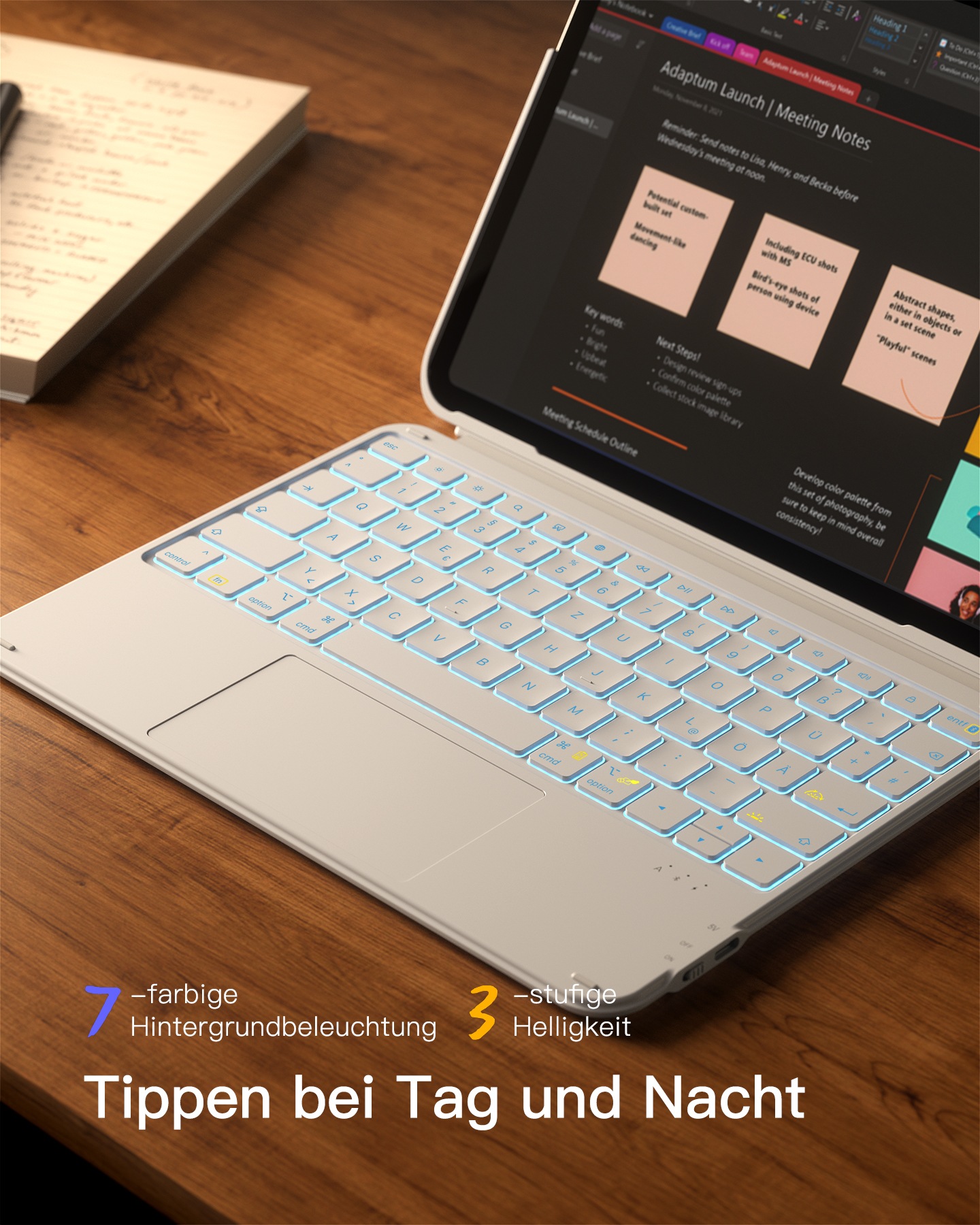 Ein beleuchtetes Laptop-Keyboard auf einem Holztisch mit Notizen daneben.
