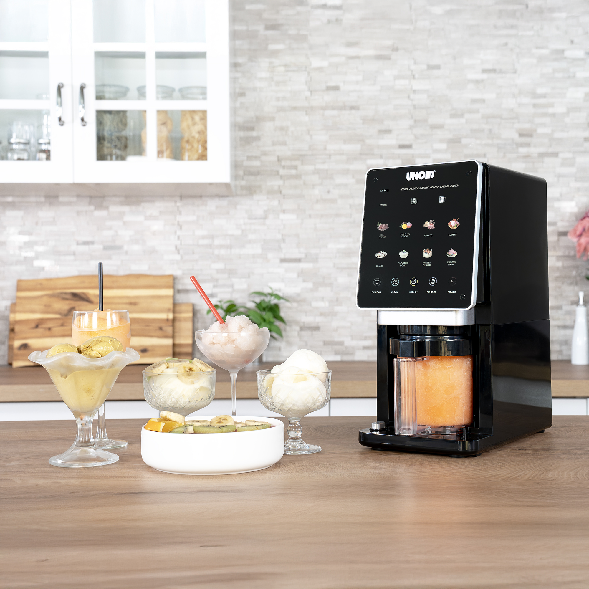 Ein schwarzer UNOLD Eismaschinen-Automat steht auf einer Holzoberfläche mit Desserts.