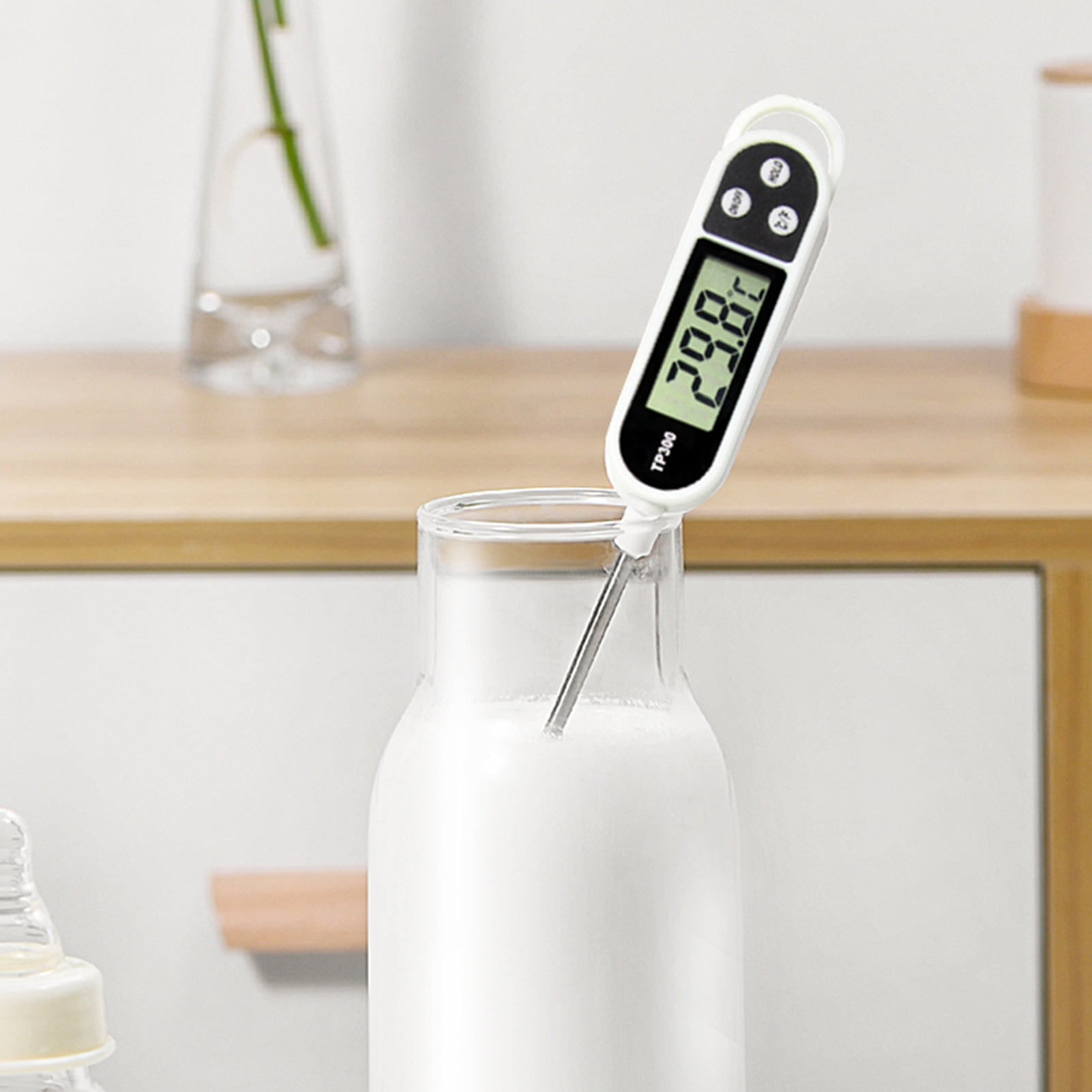 Ein digitales Thermometer misst die Temperatur einer Milchflasche.