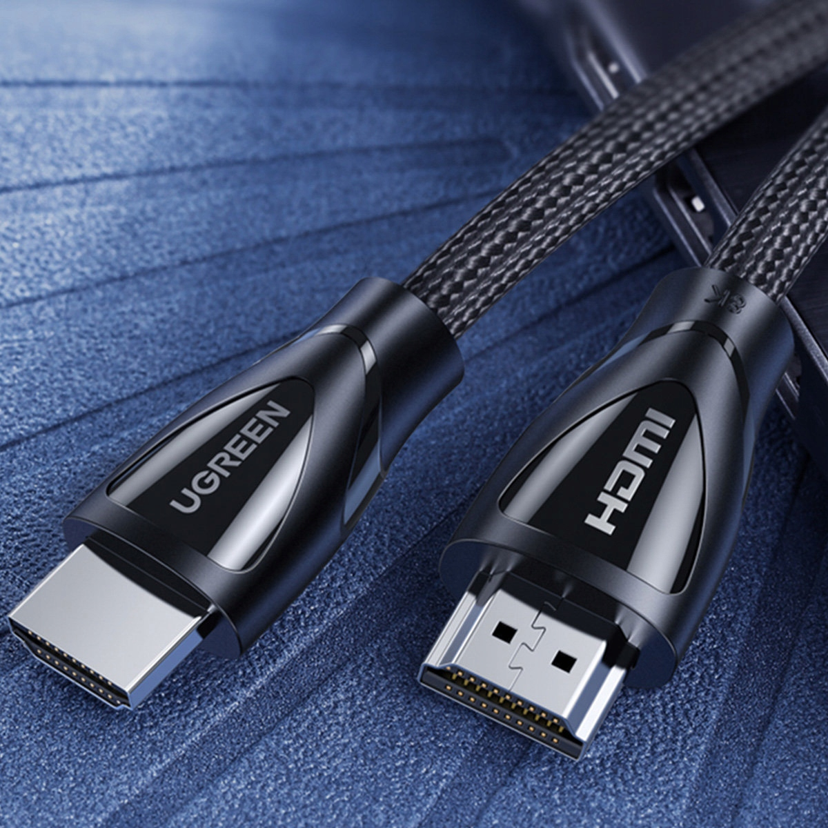 Dwa kable HDMI z logo UGREEN i HDMI na niebieskiej powierzchni.