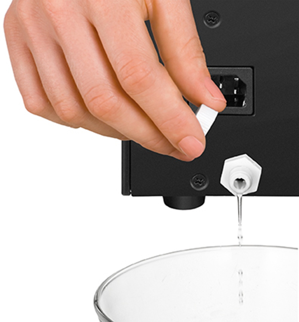 Dłoń trzymająca białą wtyczkę obok czarnego urządzenia. Ciecz kapie.