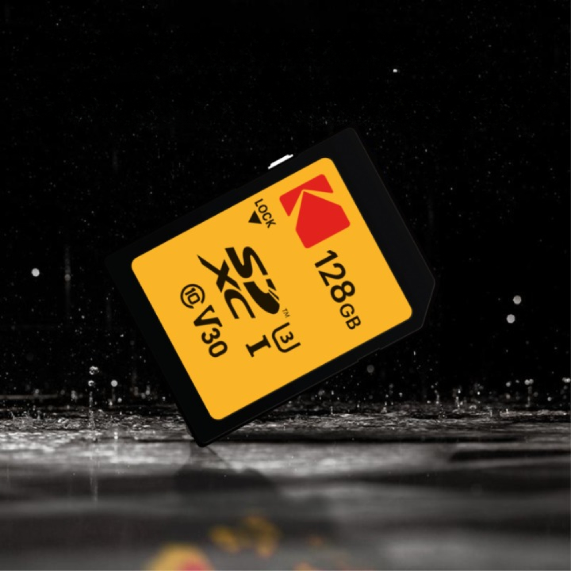 Eine gelbe SD-Karte mit 128 GB liegt auf einer nassen, dunklen Oberfläche.
