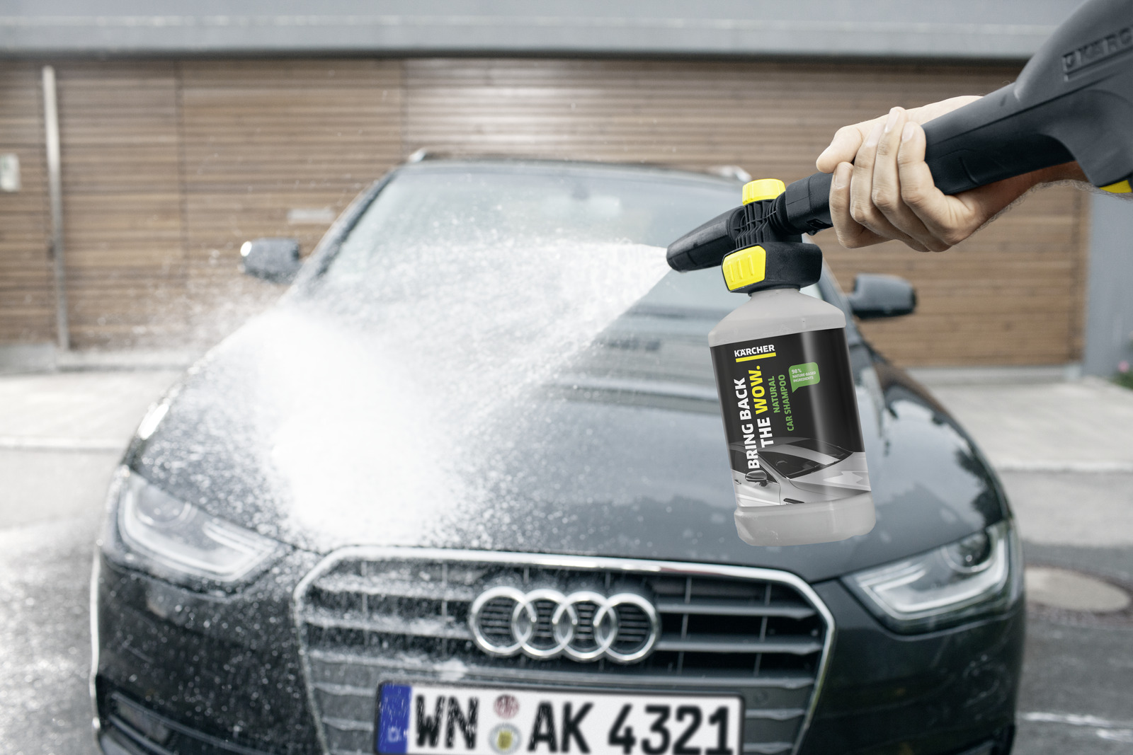 Ein Kärcher-Reiniger sprüht Schaum auf einen dunklen Audi. Das Logo ist sichtbar.