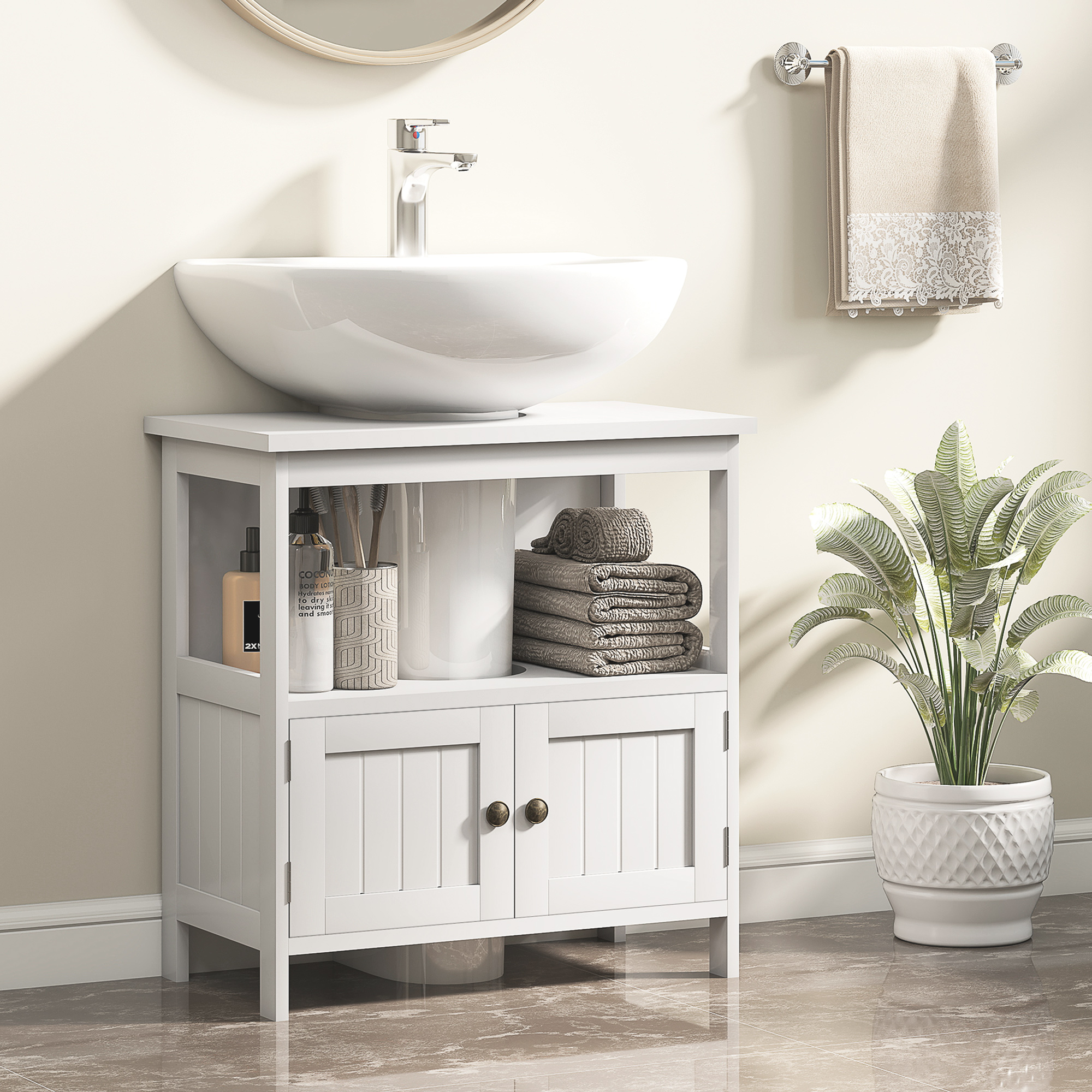Mobiletto da bagno bianco con lavandino, asciugamani e pianta.