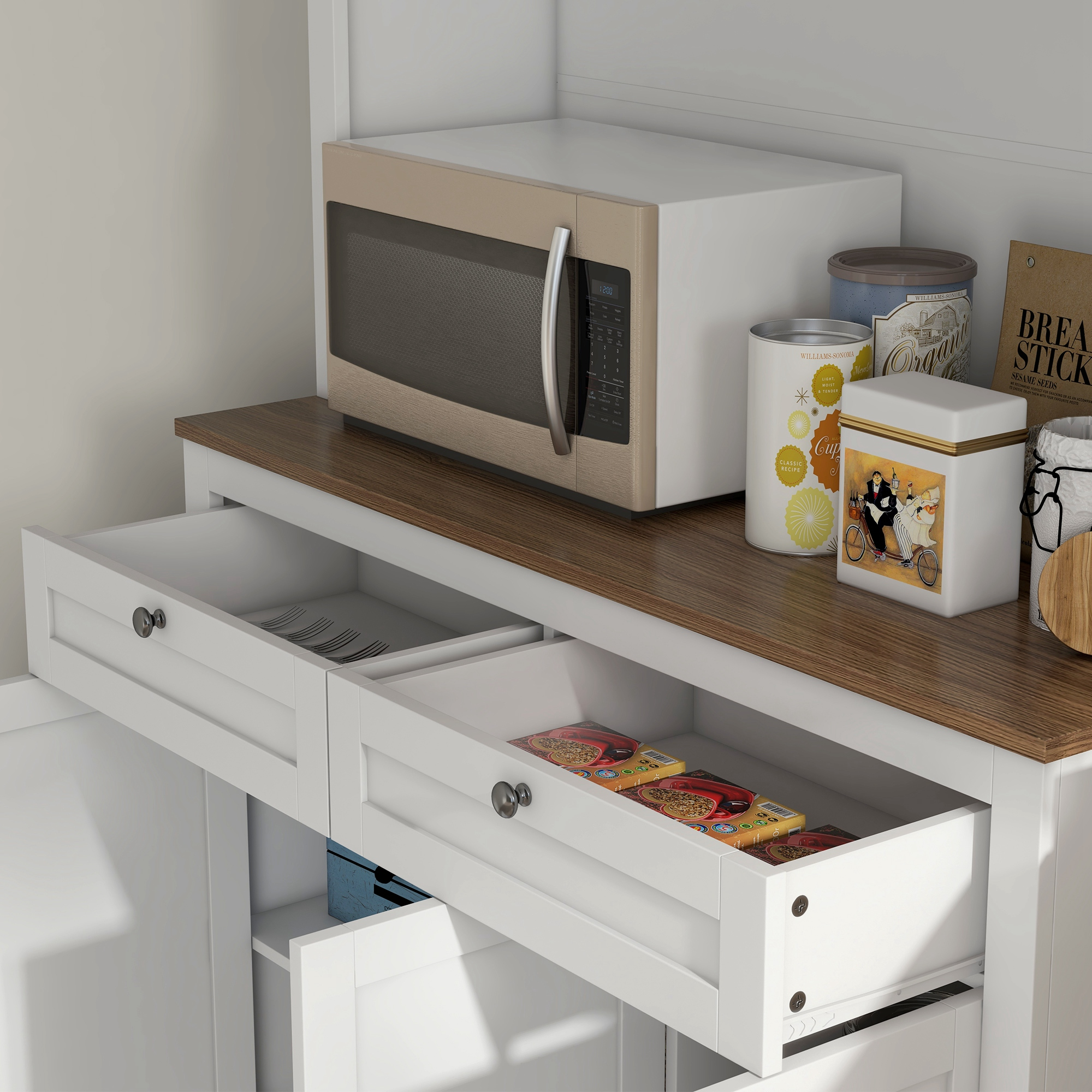 Un microondas sobre un mostrador de madera con cajones blancos abiertos. Latas y cajas en el mostrador.