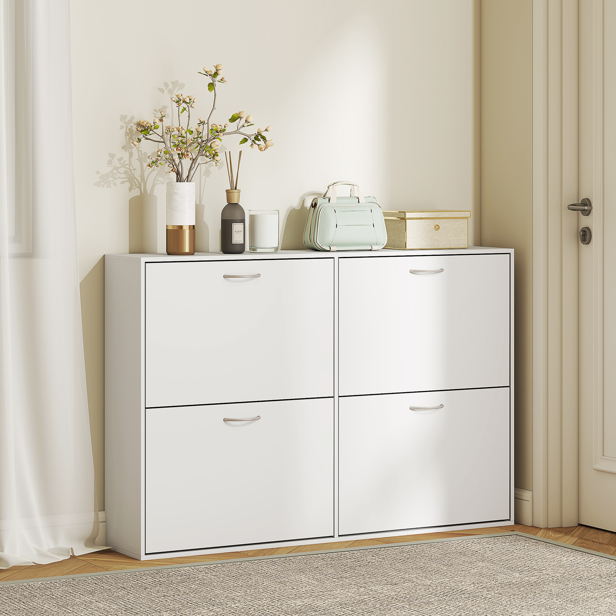 Un zapatero blanco de cuatro puertas abatibles, decorado con jarrón, difusor, vela, bolso y caja.