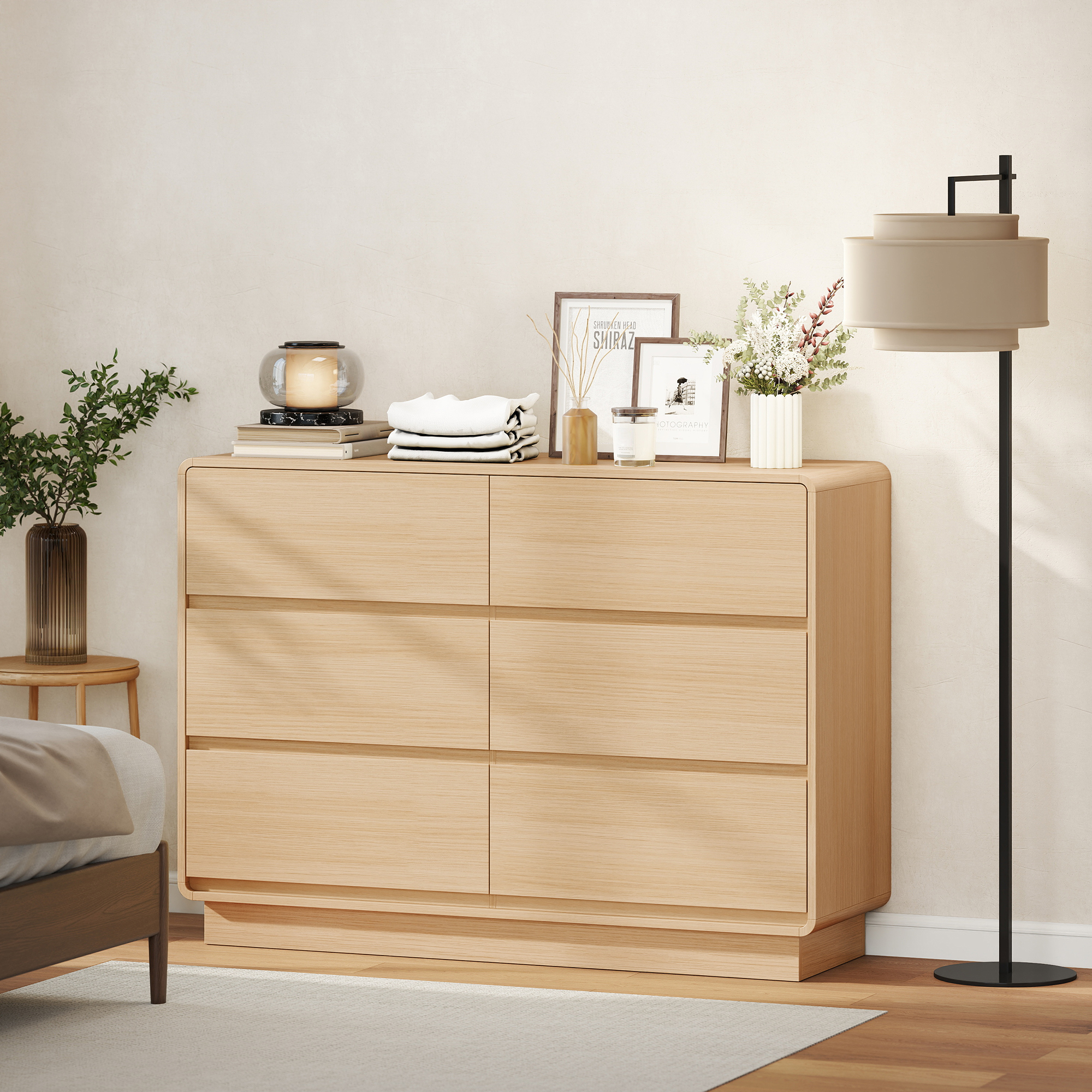 Un dormitorio luminoso con cómoda de madera, mesita de noche, lámpara y cama.