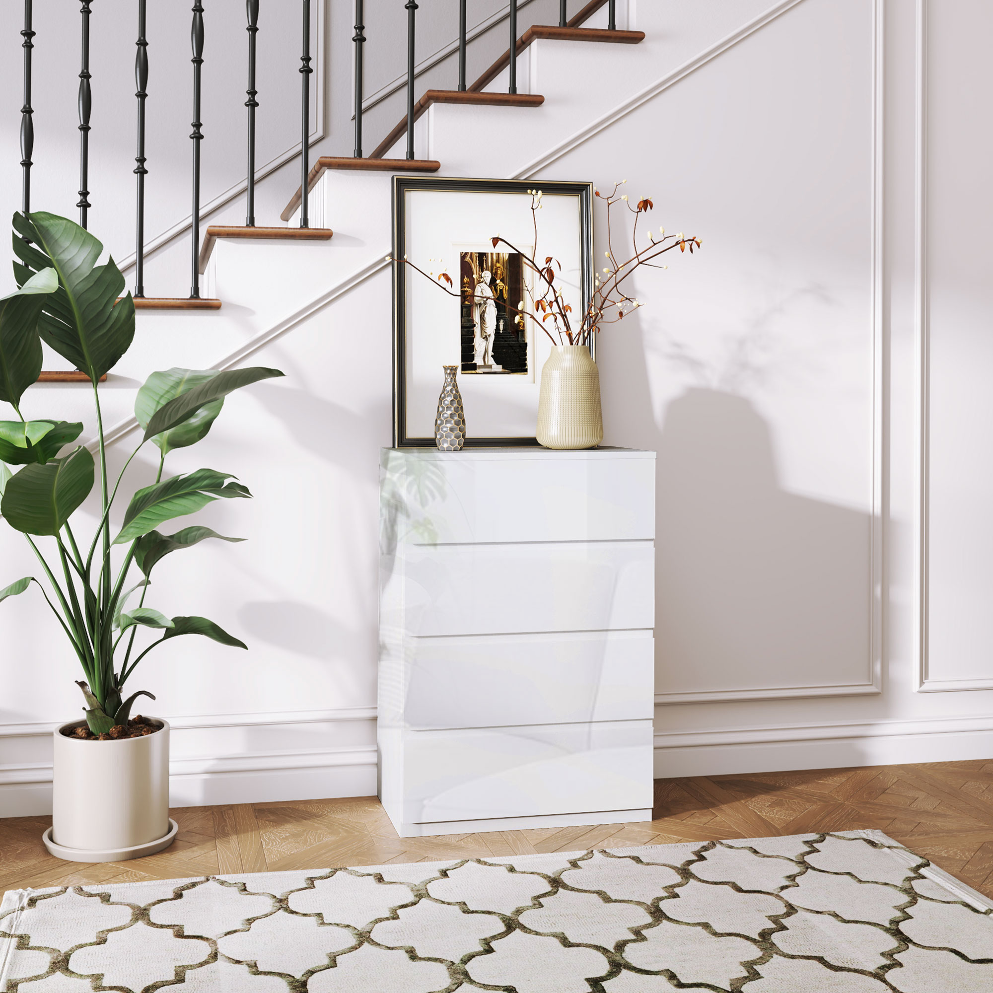 Una cómoda blanca de cuatro cajones junto a una escalera y una planta.