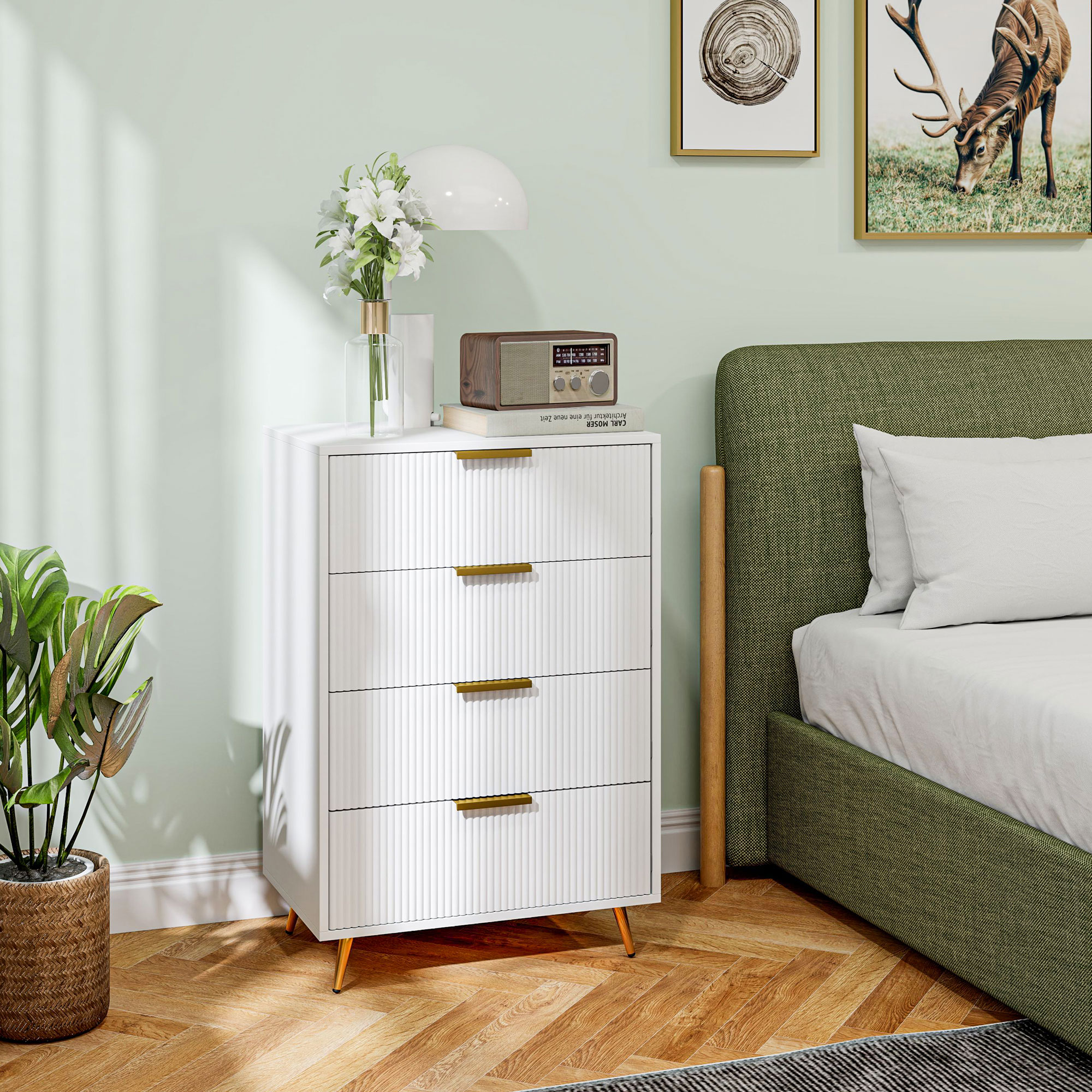 Una escena de dormitorio con una cómoda blanca, una cama tapizada verde y arte de pared, todo sobre un suelo de madera.