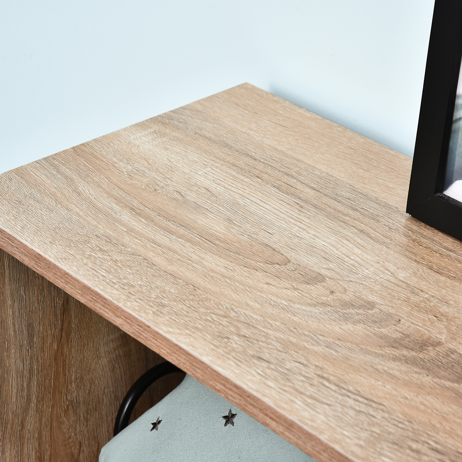 Superficie de madera con marco negro y cojín azul con estrellas.