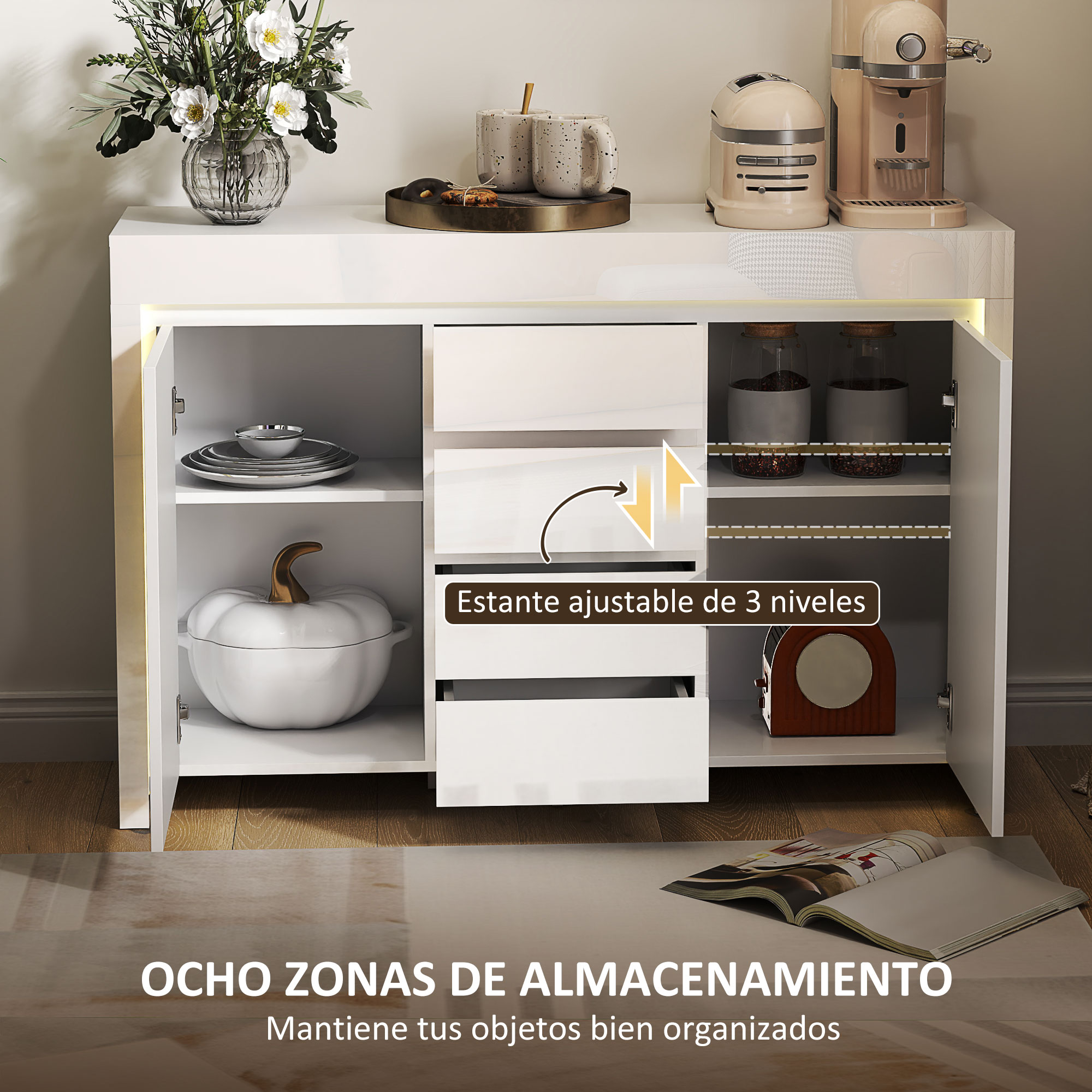 Un aparador blanco con puerta abierta. Flores, tazas y electrodomésticos encima.