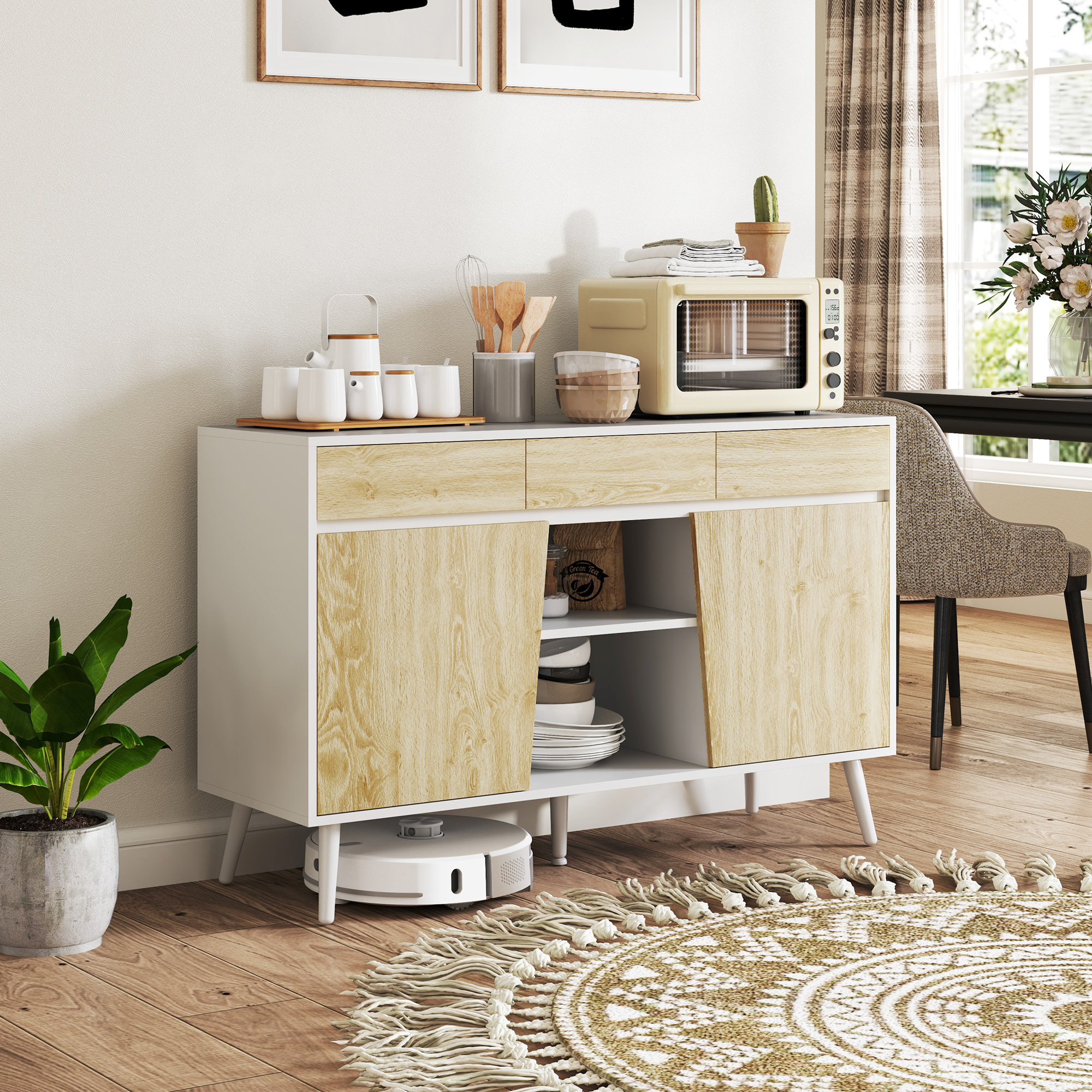Un aparador moderno con acabado blanco y madera, con utensilios, microondas y decoración.