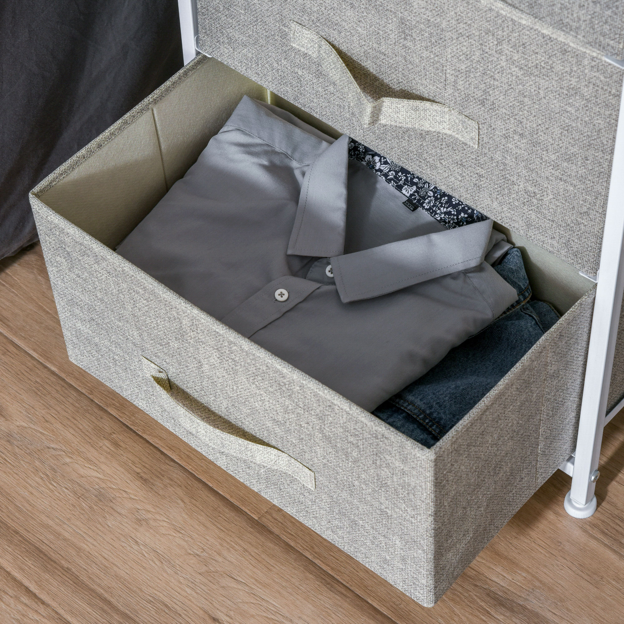 Una camisa gris y jeans en un cajón de tela sobre suelo de madera.