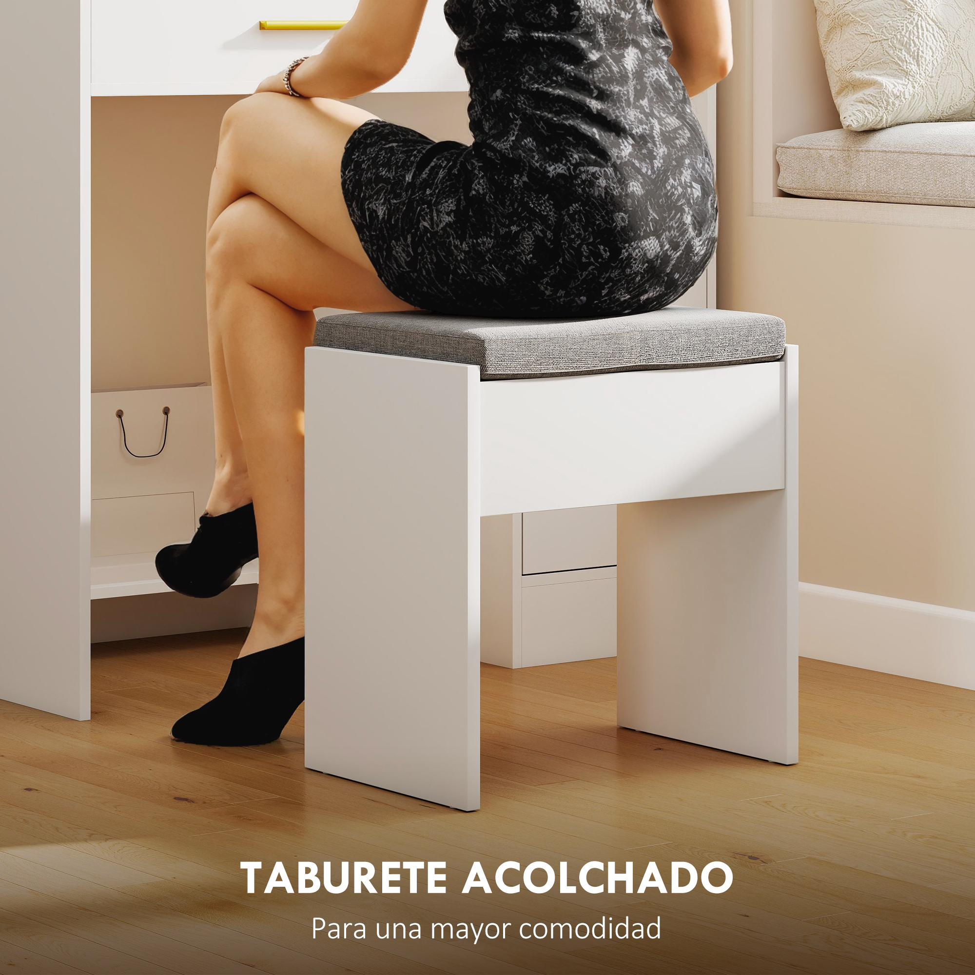 Una mujer con vestido negro se sienta en un taburete blanco con cojín gris.