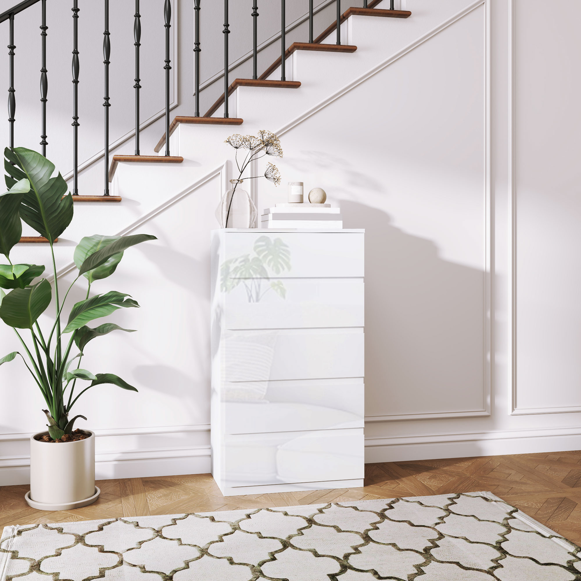Un tocador blanco junto a una escalera con barandilla negra y una planta.