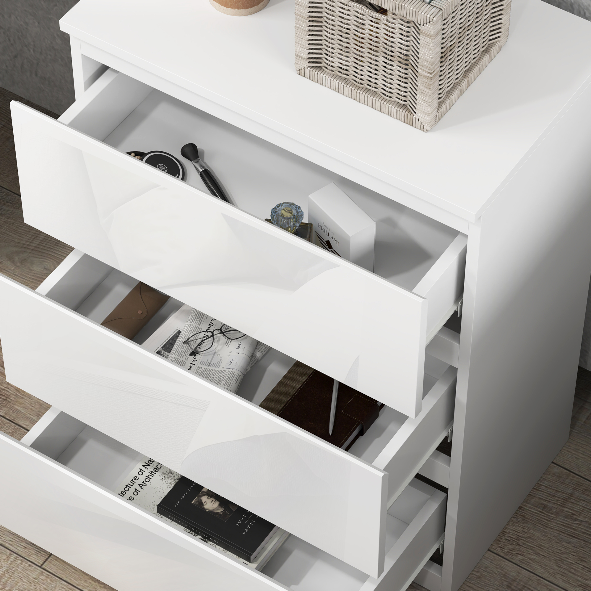 Cómoda blanca con cajones abiertos que contienen cosméticos, gafas, libros y un cuaderno.