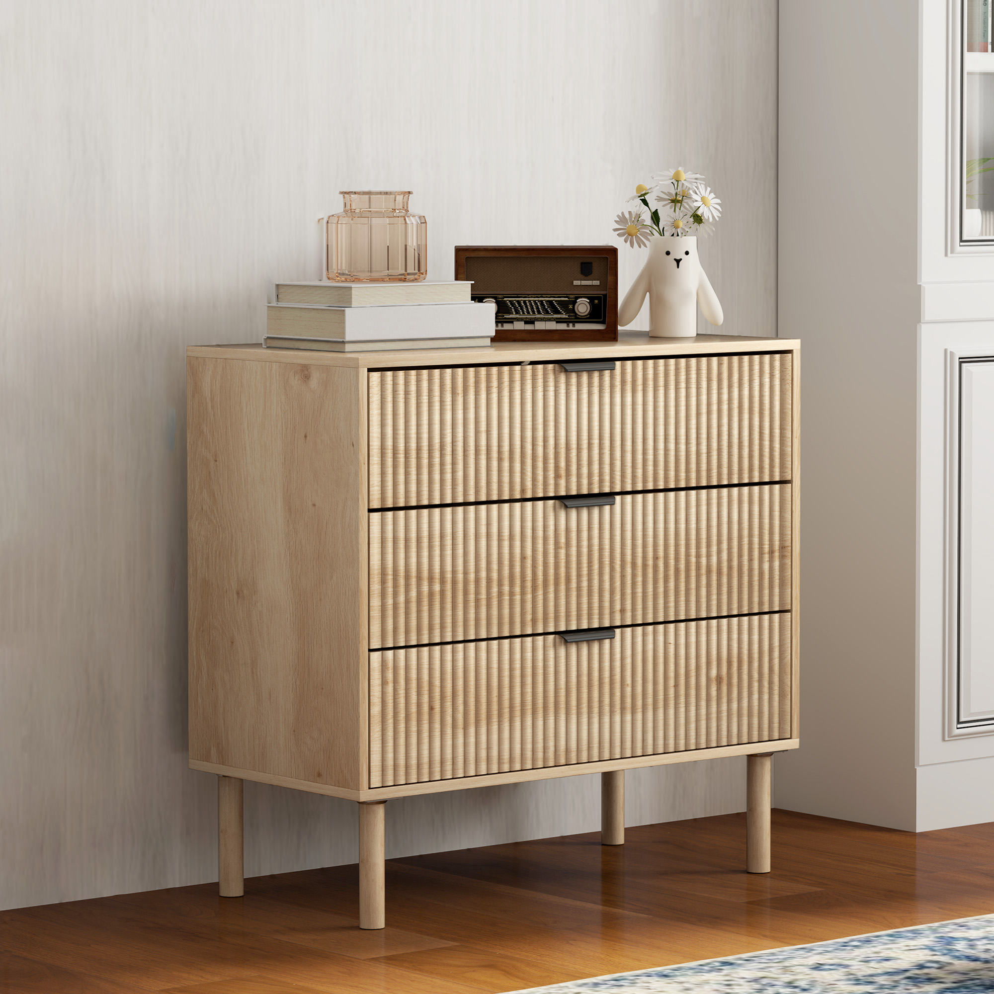 Cómoda de madera clara con tres cajones y frentes acanalados.