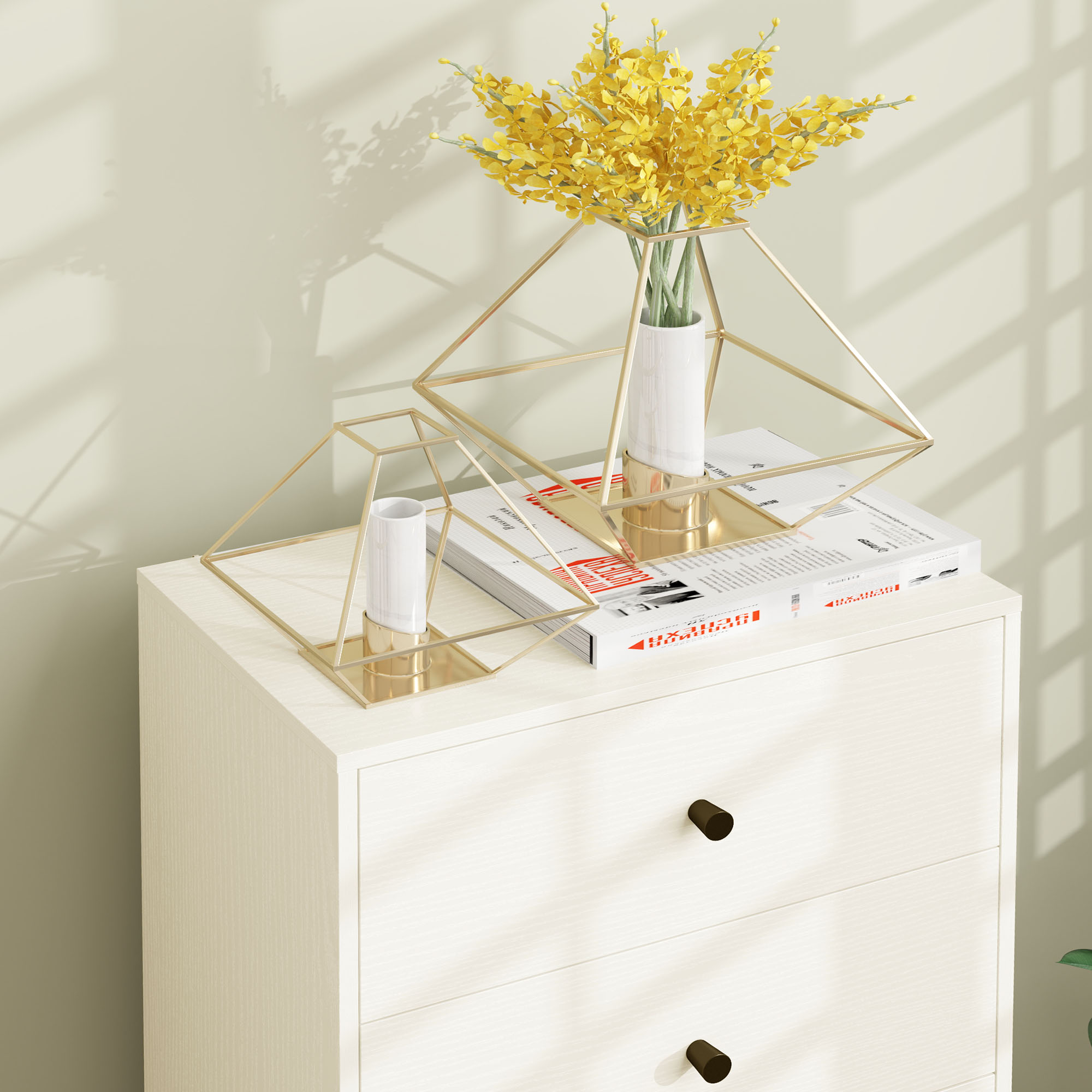 Cómoda blanca con libros y decoración geométrica dorada con flores amarillas.
