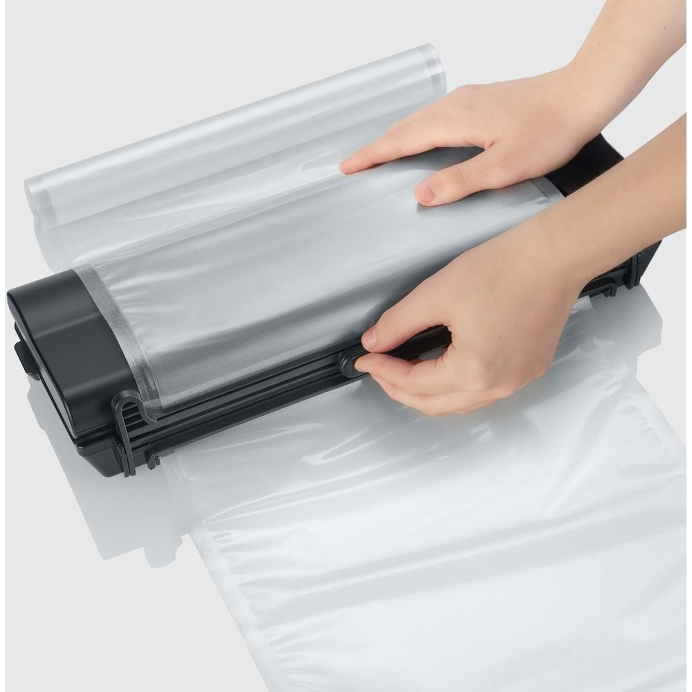 Ręce obsługujące pakowarkę próżniową z plastikową torbą.