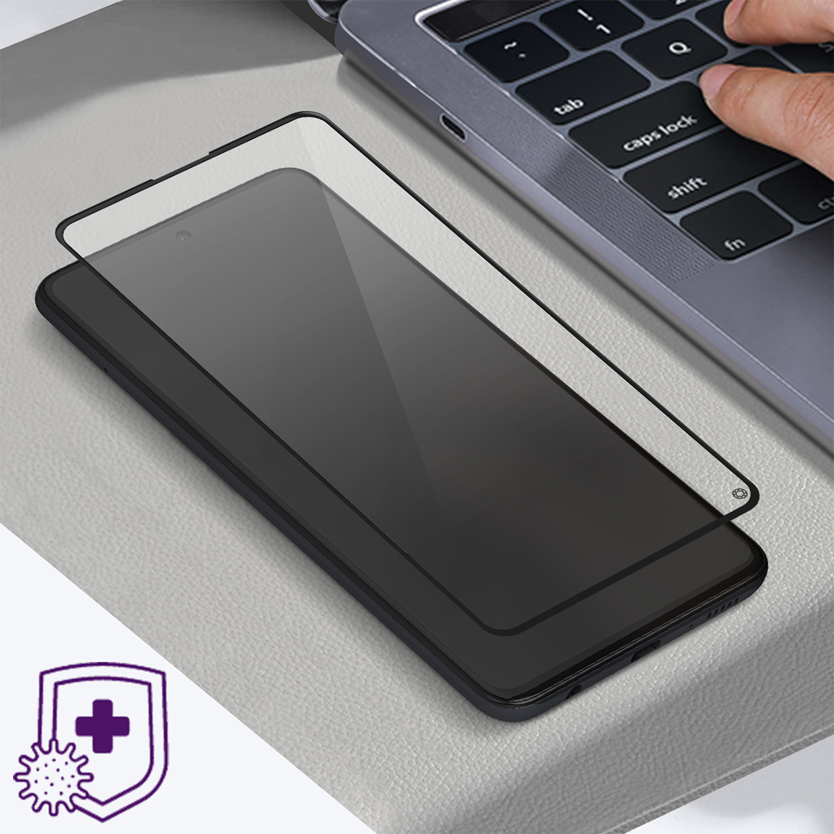 Uno smartphone con pellicola protettiva accanto a una tastiera di laptop. Uno scudo con croce e icona di virus.