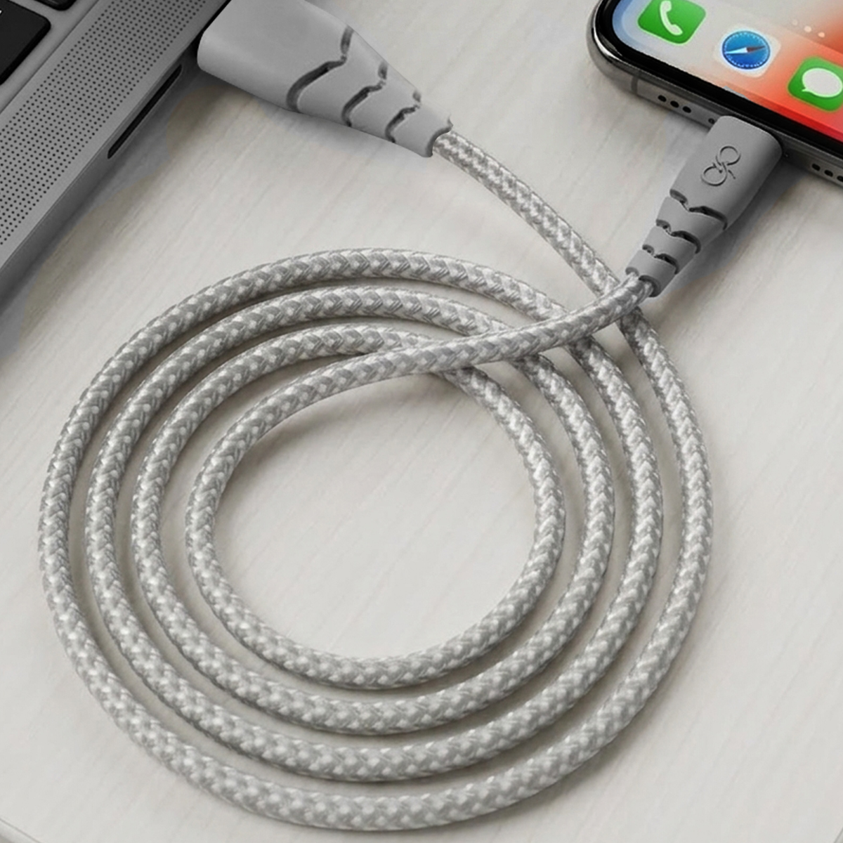 Un cavo di ricarica grigio collega uno smartphone a un laptop.