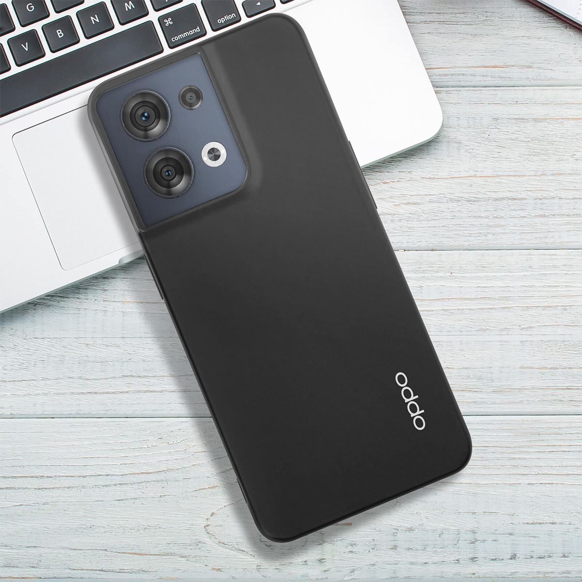 Schwarzes Smartphone mit Kamera-Array auf Tastatur und Holztisch.