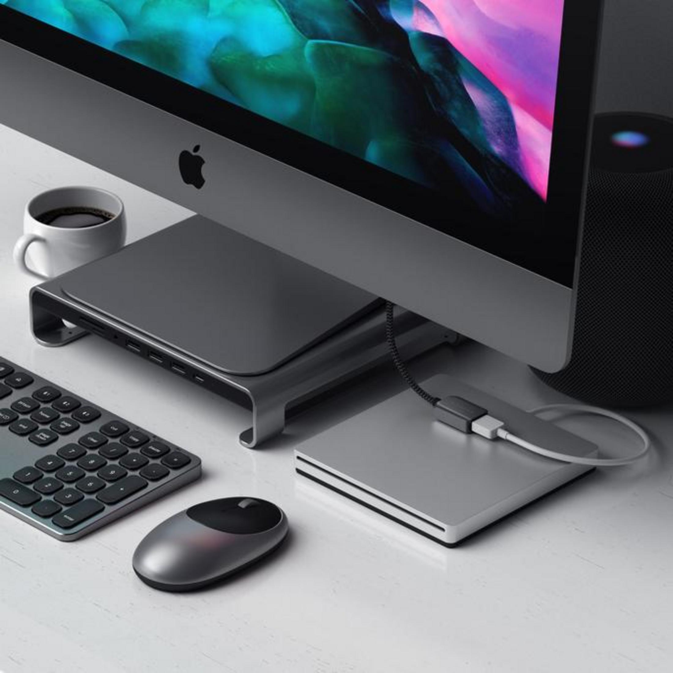 Ein iMac mit Tastatur, Maus, einem Hub und Kaffee auf einem Schreibtisch.
