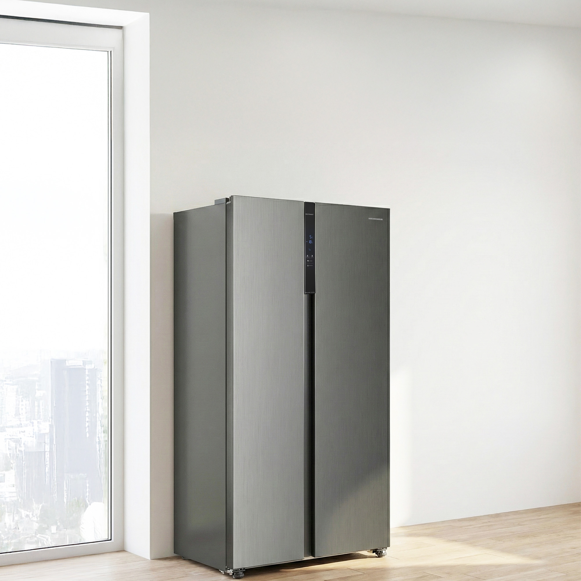 A gray, double-door refrigerator stands next to a large window.