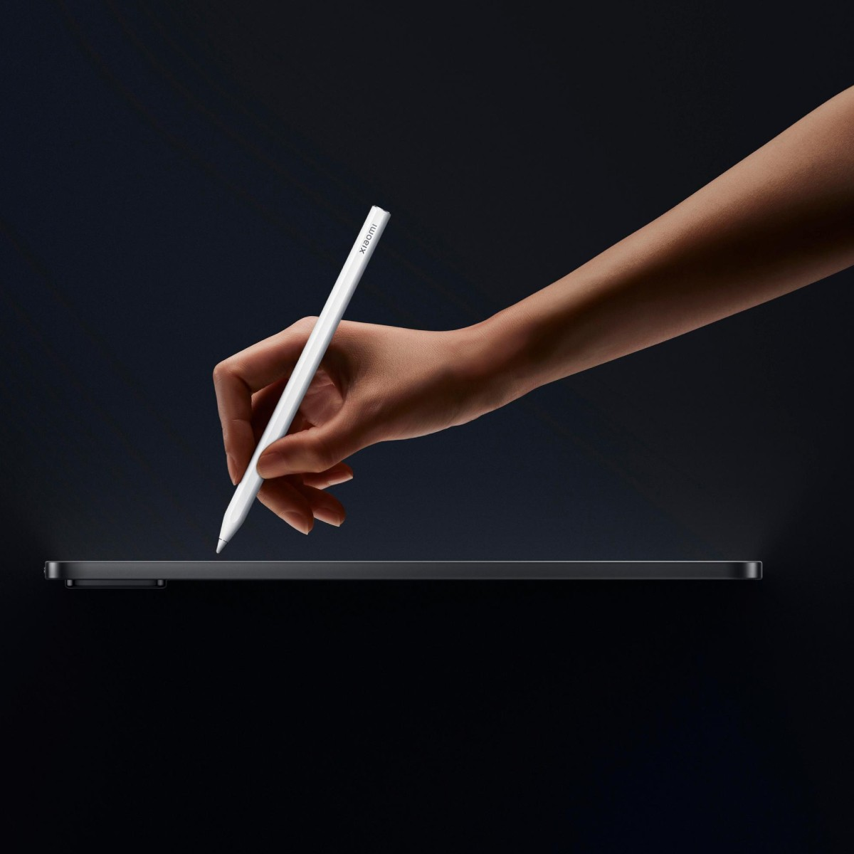 Eine Hand hält einen weißen Xiaomi-Stift über einem dunklen Tablet.