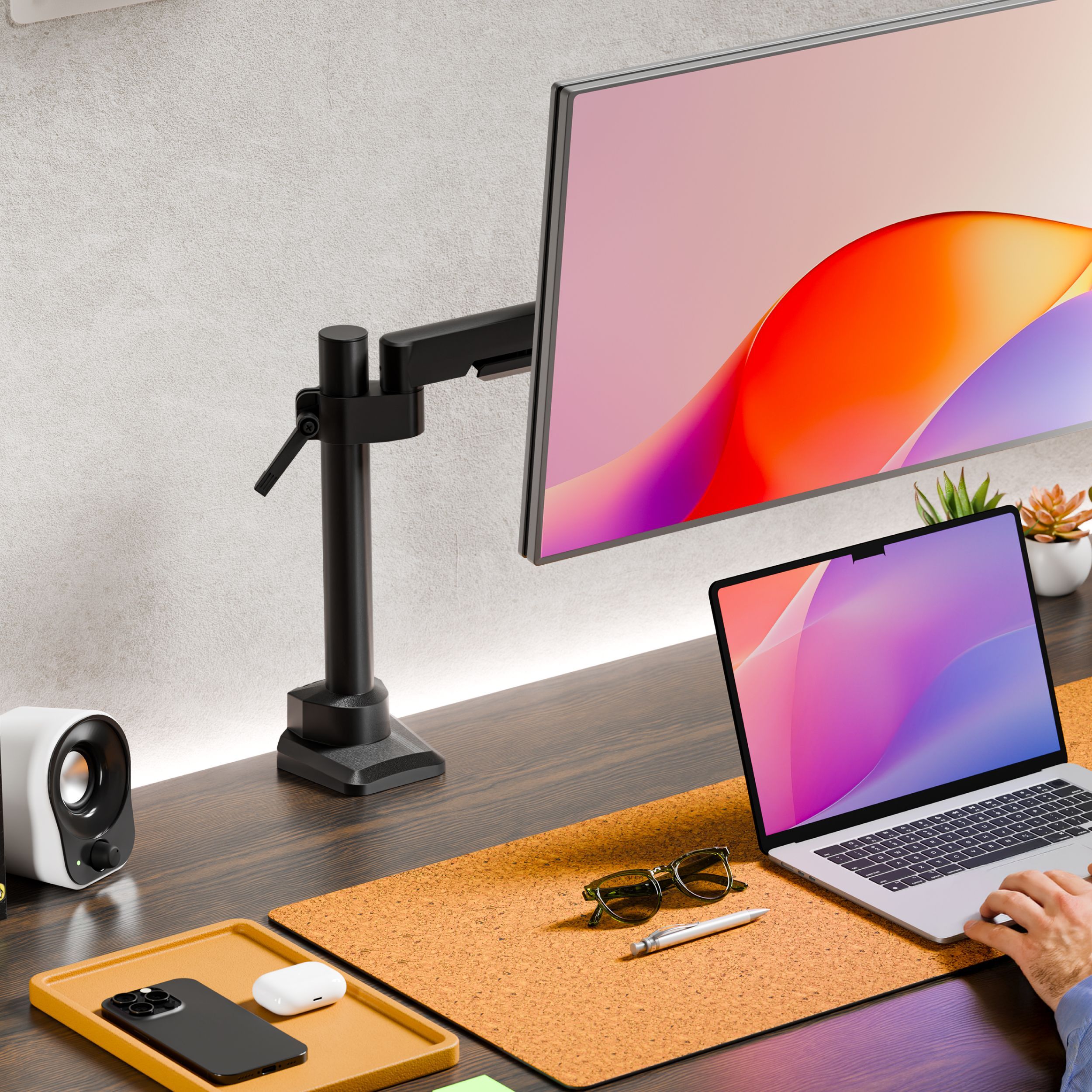 Scrivania con laptop, monitor, telefono, auricolari, occhiali e penna.