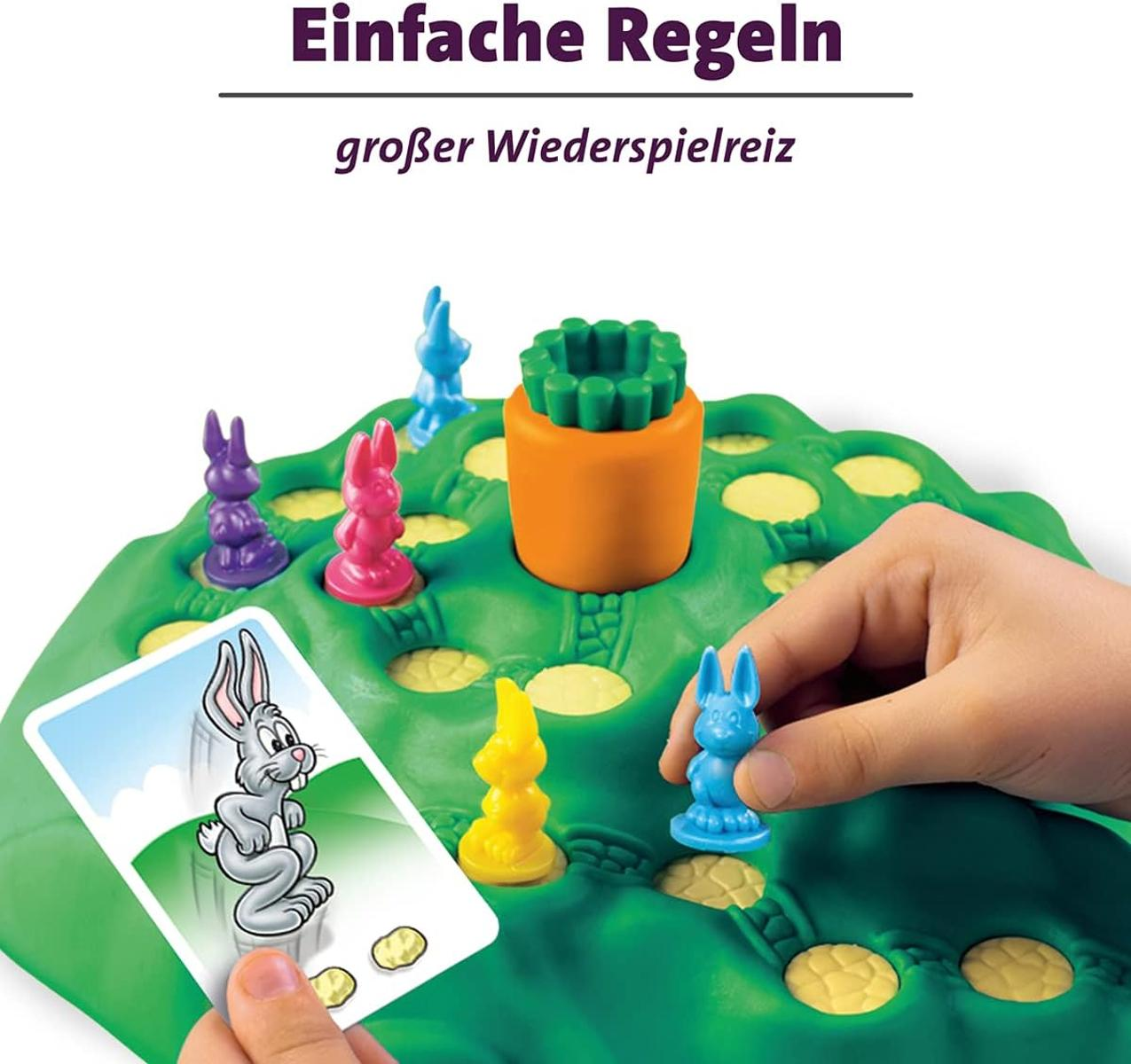 Un niño juega a un juego de mesa con figuras de conejitos y una zanahoria.