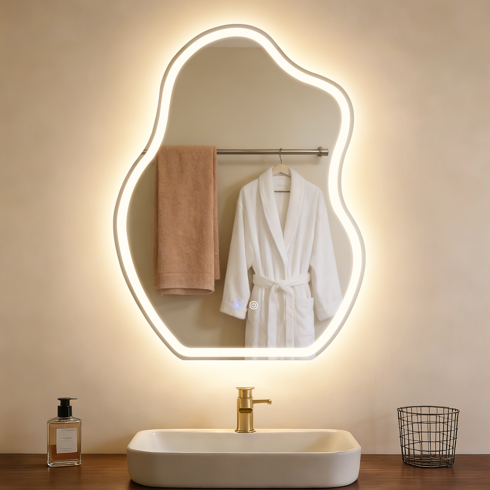 Baño con espejo iluminado, bata blanca, toalla marrón y lavabo.