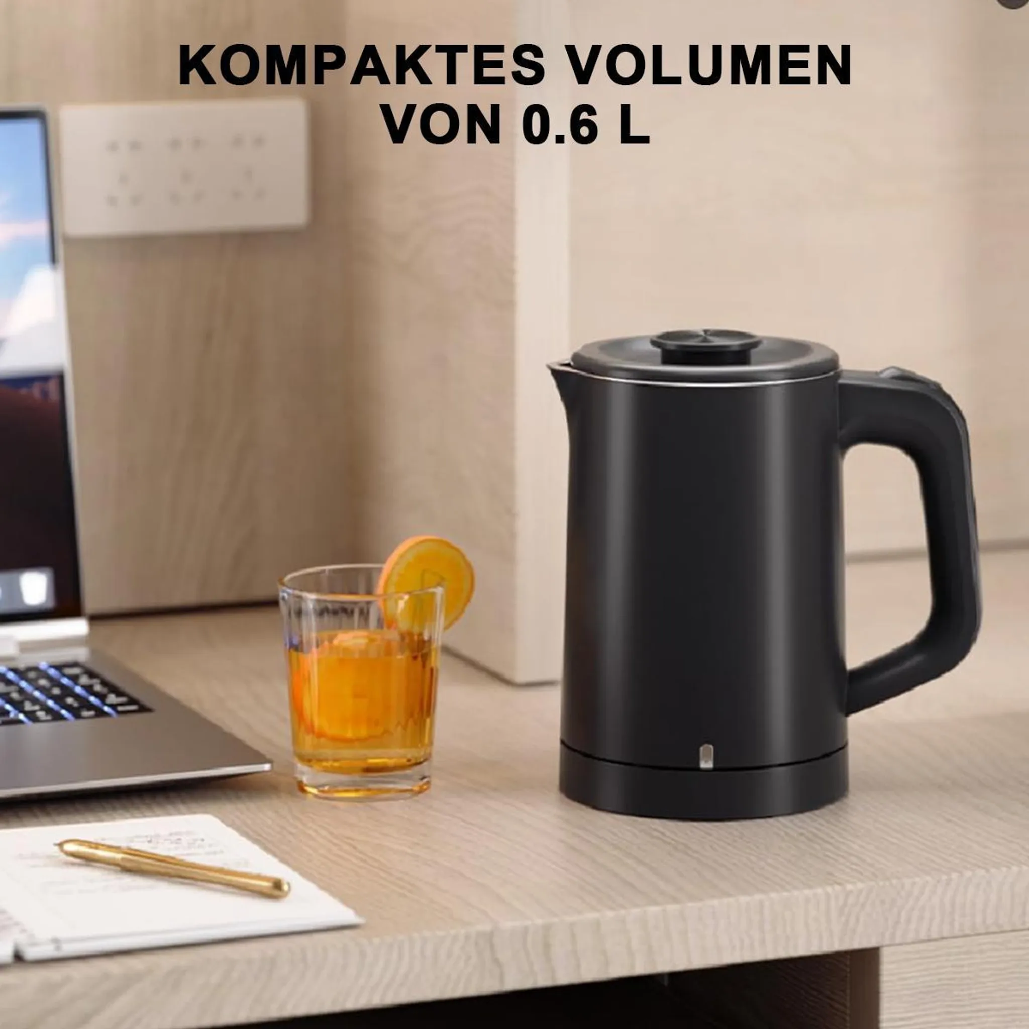 Schwarzer Wasserkocher mit Glas, Laptop und Stift auf einem Holztisch.