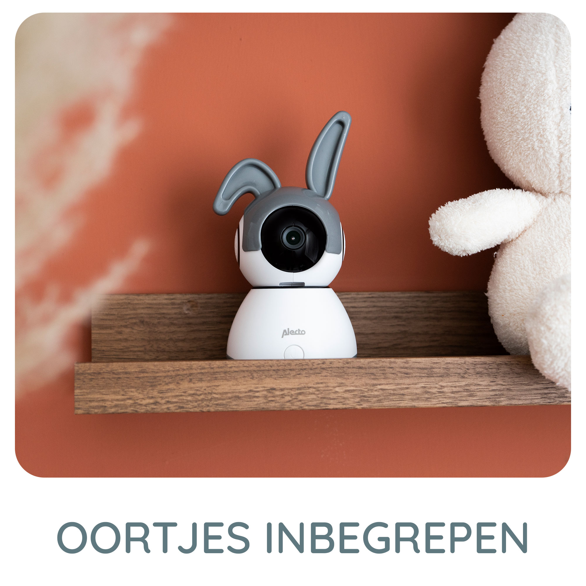 Un babyphone blanc avec des oreilles de lapin est posé sur une étagère à côté d'un ours en peluche.
