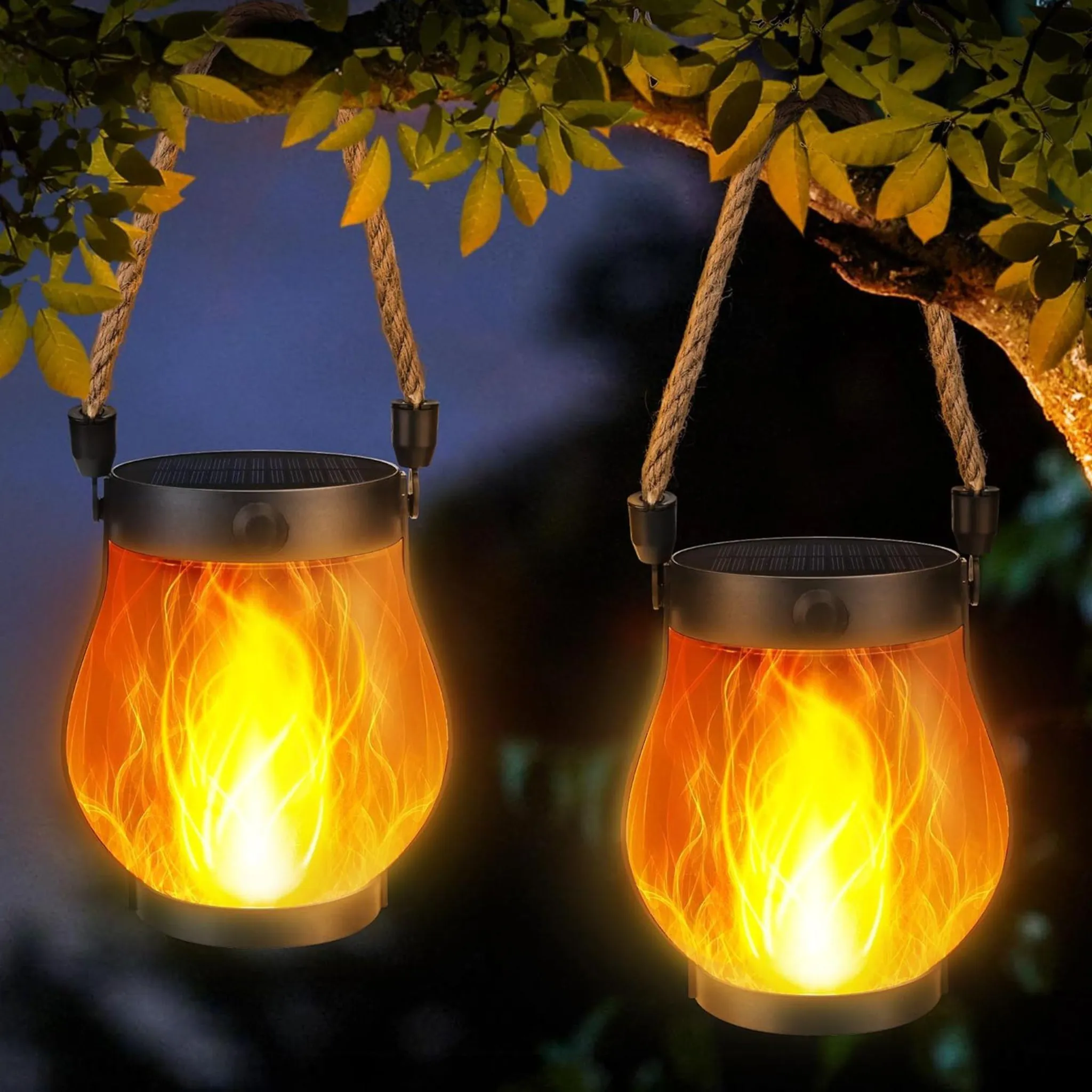 Zwei Solar-Laternen mit Flammeneffekt hängen an Seilen von einem Baum.