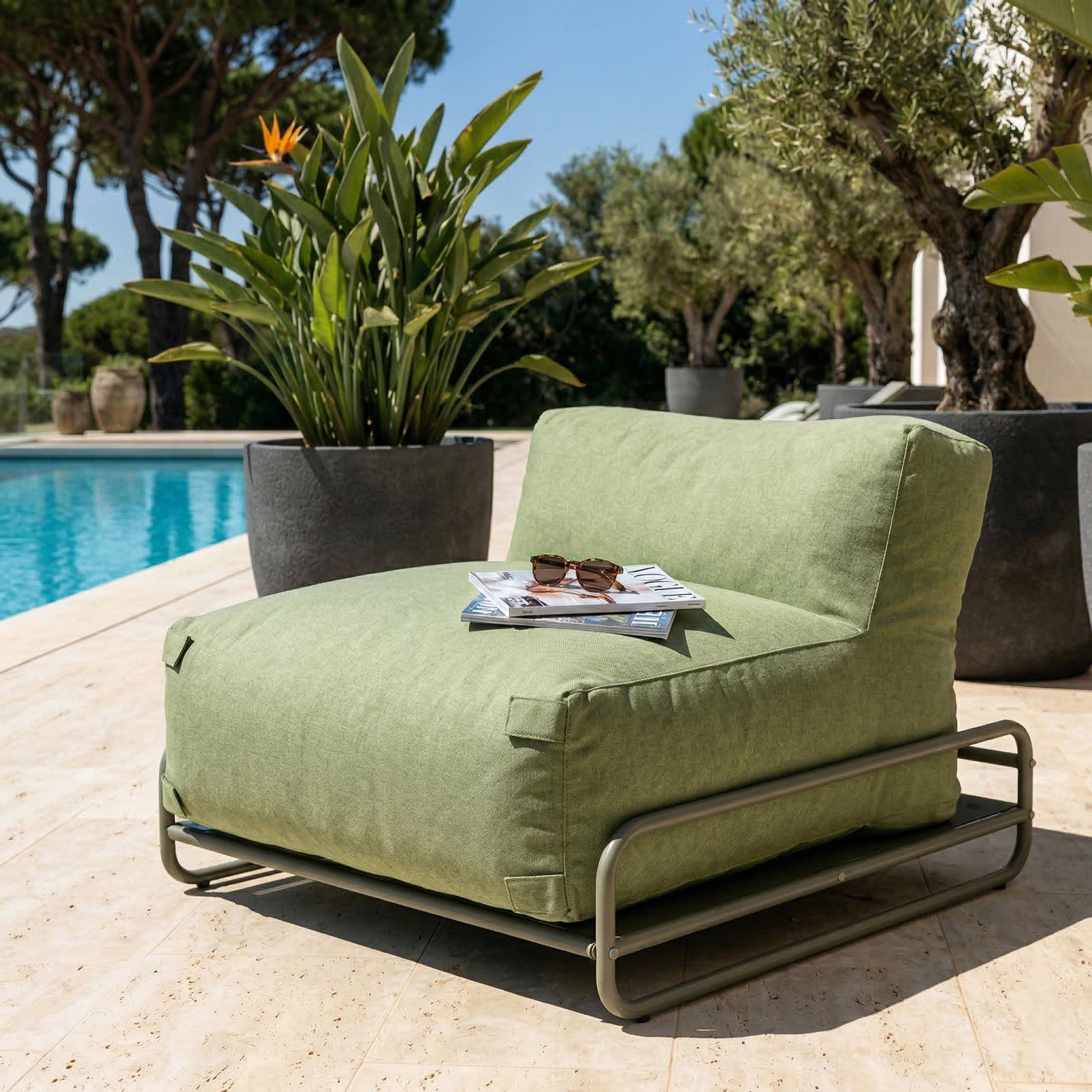 Ein grüner Sessel mit Zeitschriften und Sonnenbrille am Pool.