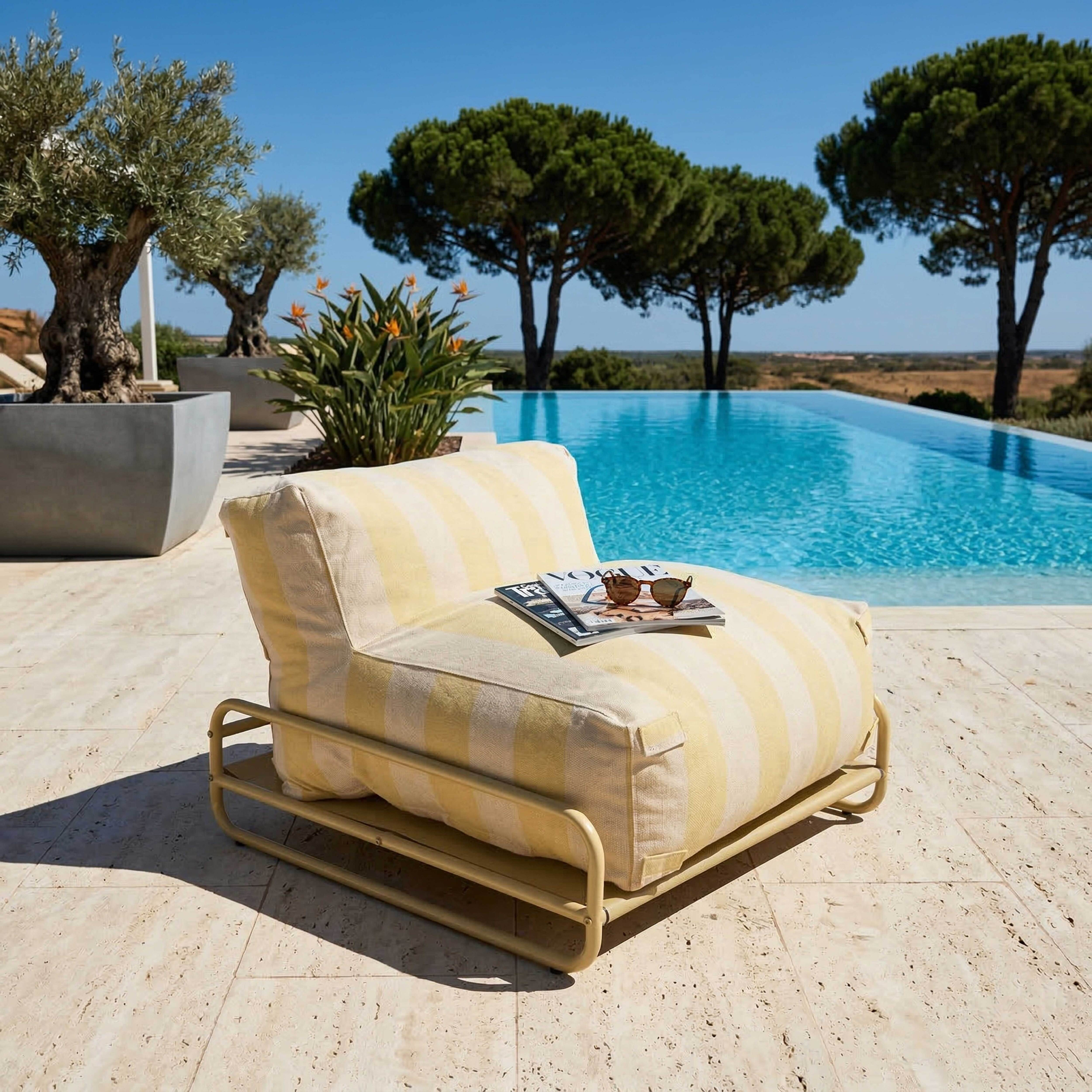 Gestreifter Sessel am Pool mit Zeitschriften und Sonnenbrille.