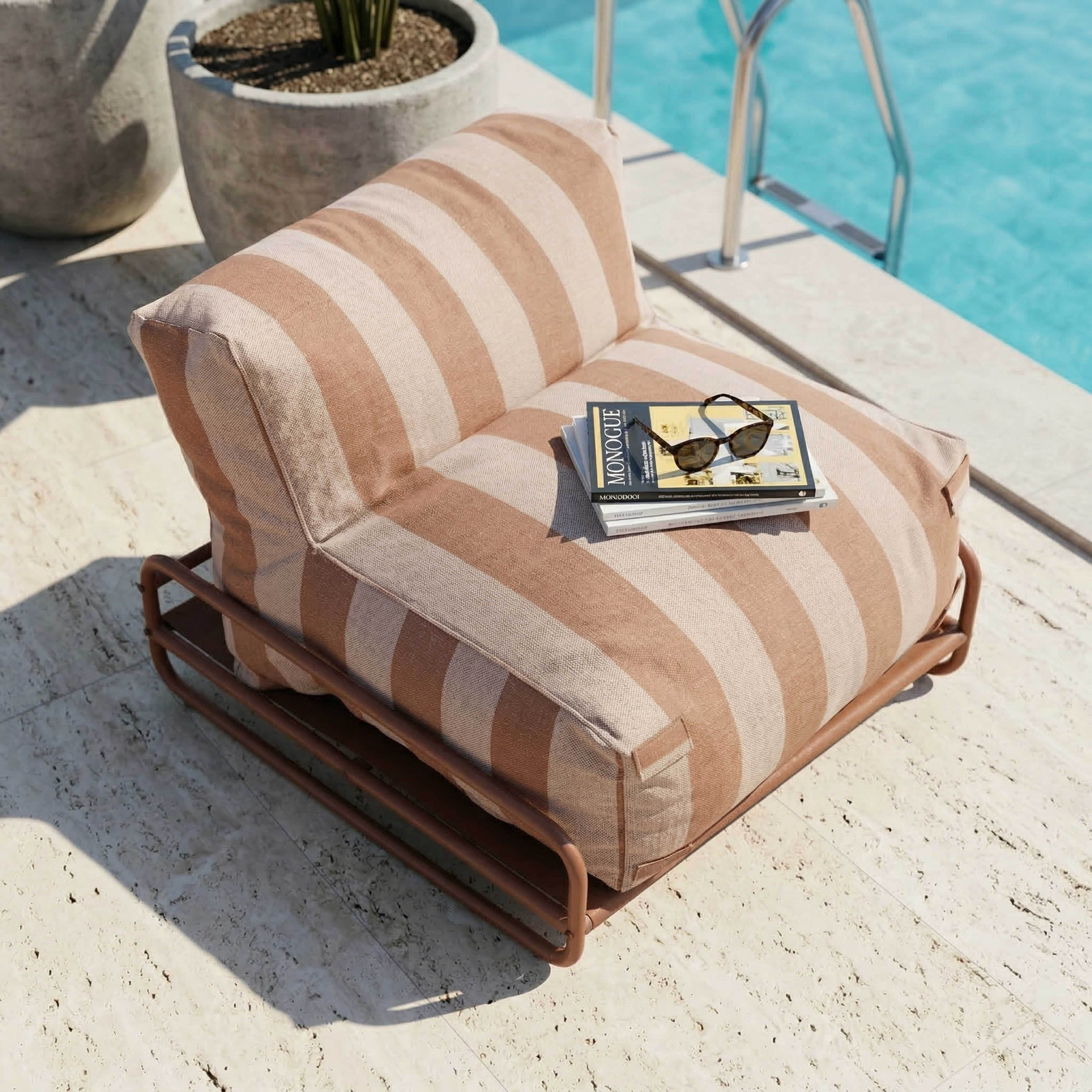 Gestriefter Sessel am Pool mit Büchern und Sonnenbrille.