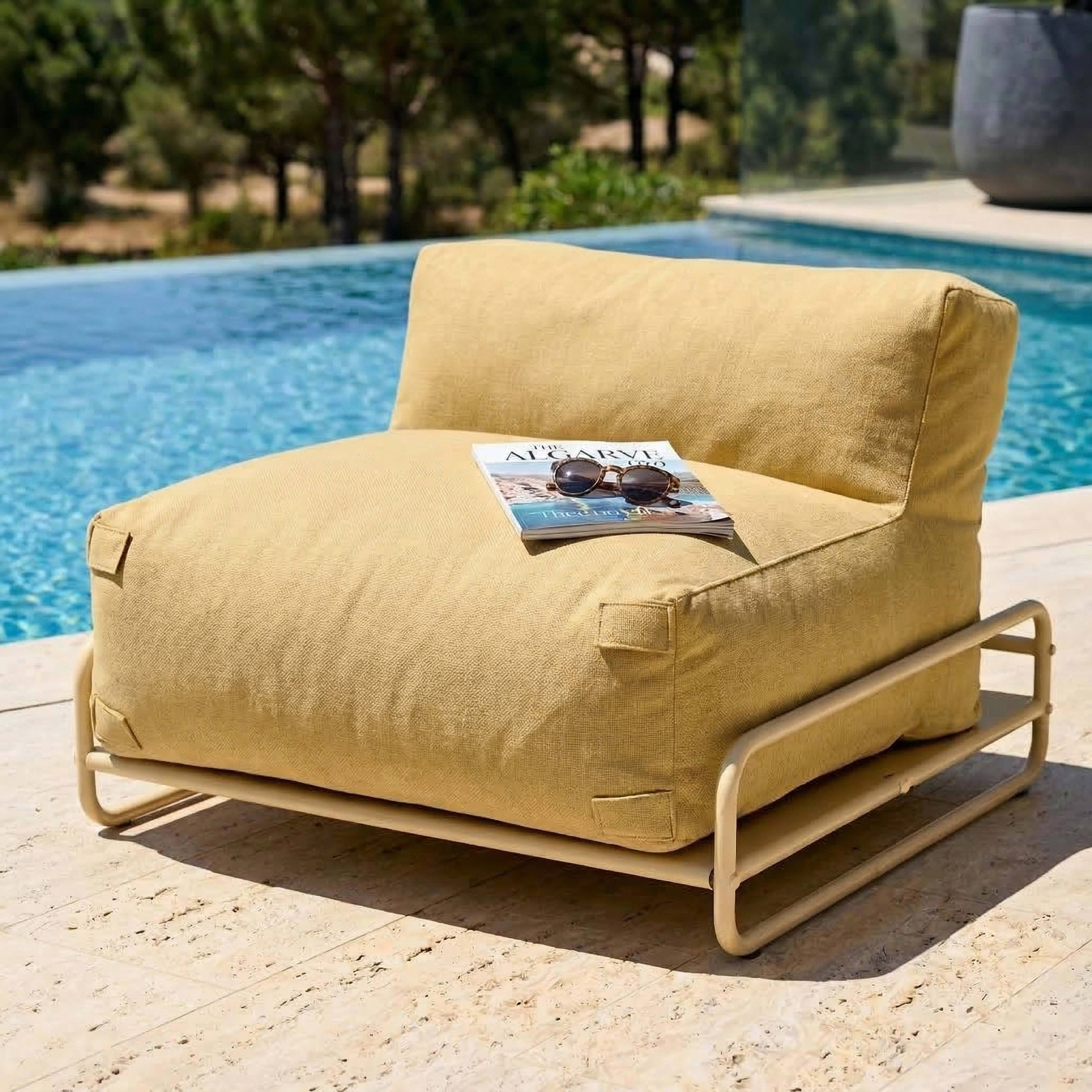 Ein gelber Sessel mit einem Magazin und Sonnenbrille steht am Pool.