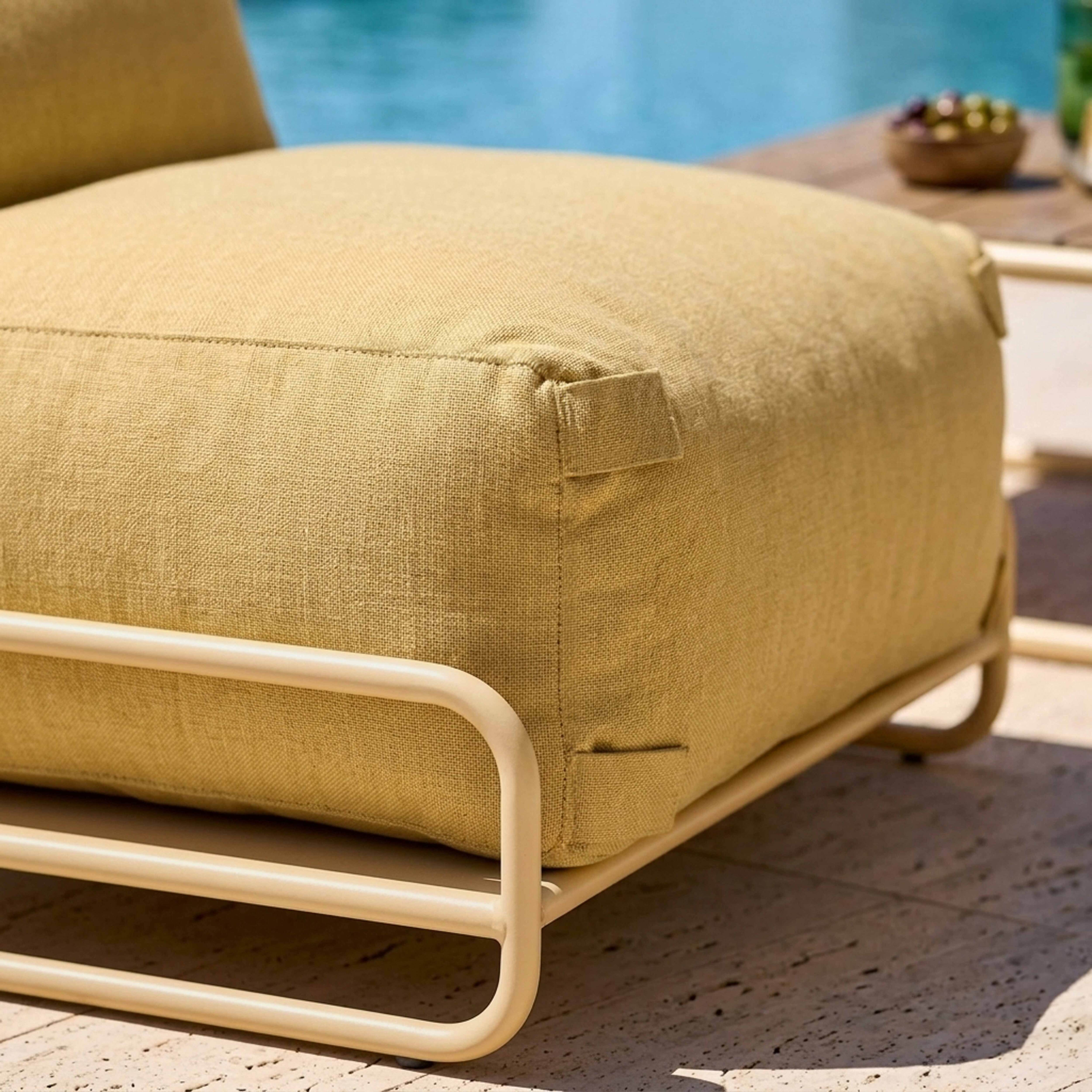 Ein gelbes Outdoor-Sitzmöbel mit Metallgestell am Pool.