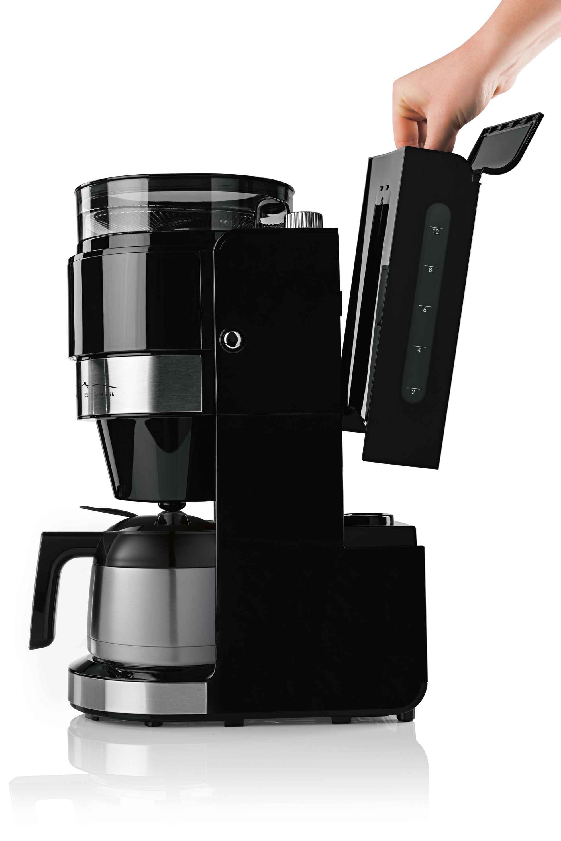 Eine Hand füllt Wasser in einen schwarzen Kaffeeautomaten mit Glaskrug.