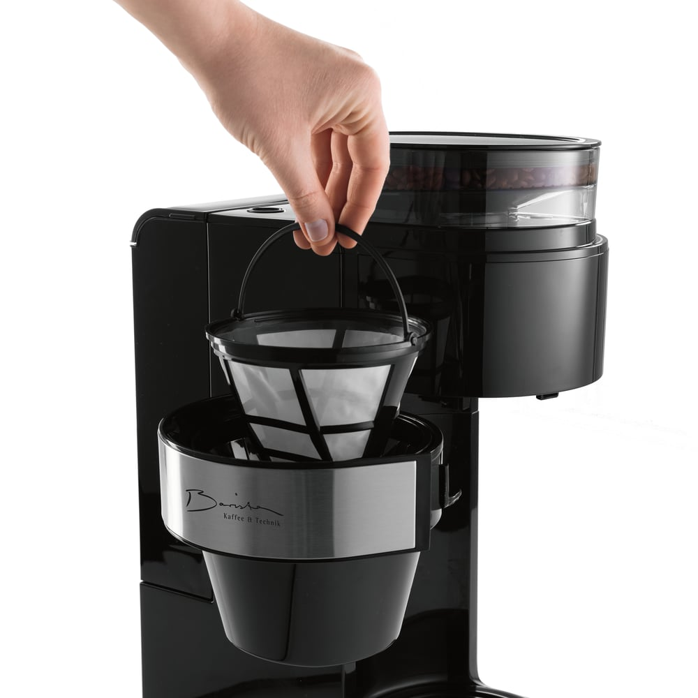 Eine Hand setzt einen Kaffeefilter in eine schwarze Kaffeemaschine ein.