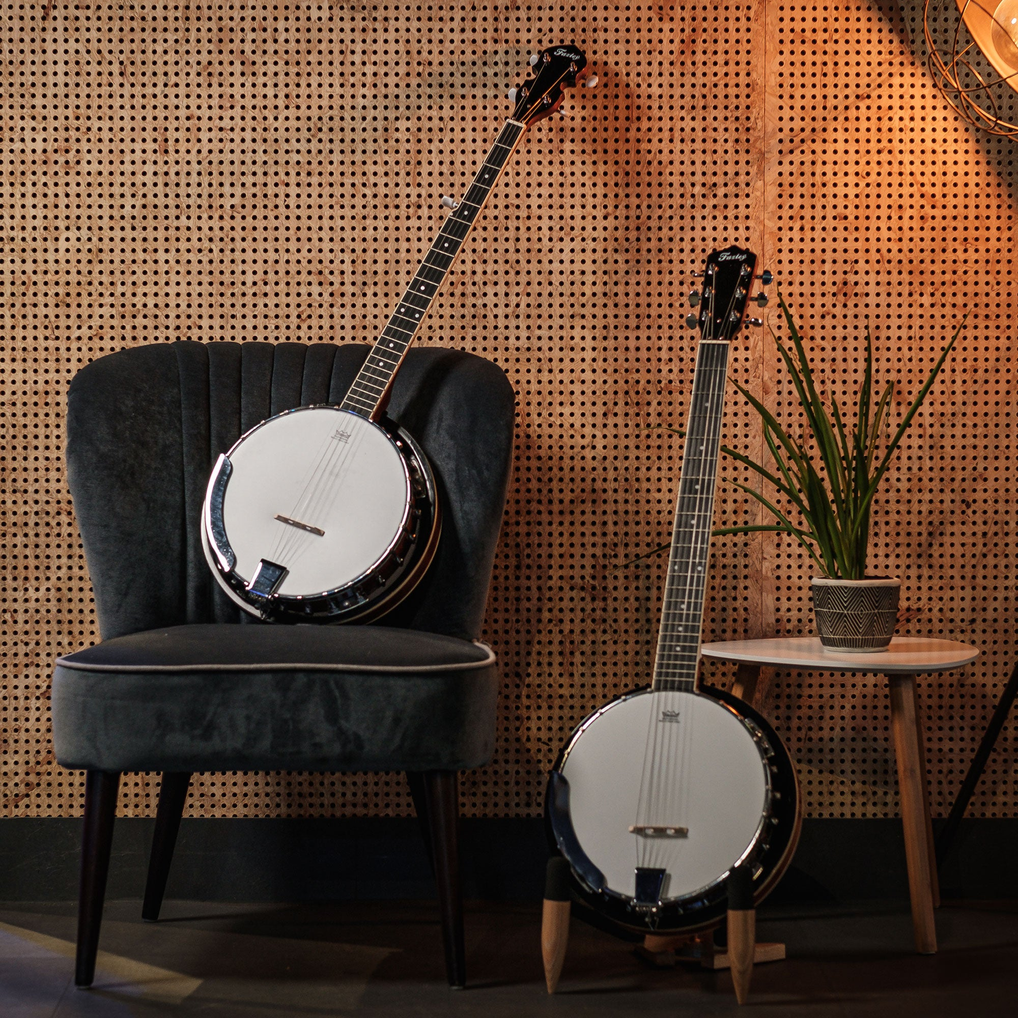 Twee banjo's staan voor een geperforeerde houten muur. Eén op een stoel, de ander op de vloer.